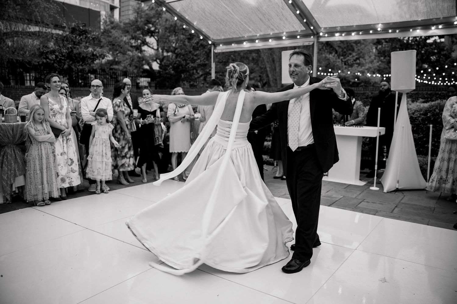 A joyful dance moment during a wedding reception on a white dance floor.
