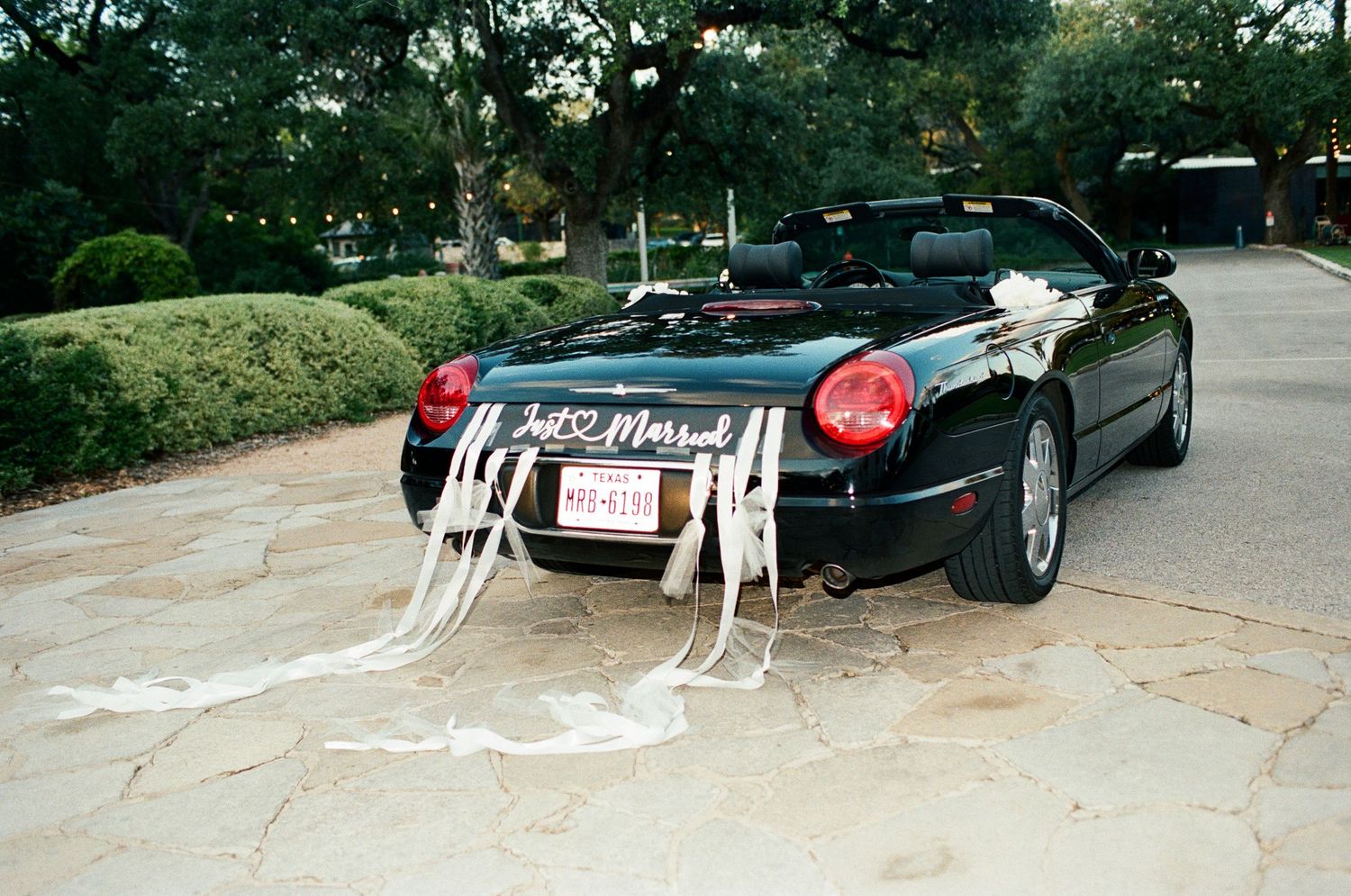A black vintage sports car parked in a driveway.