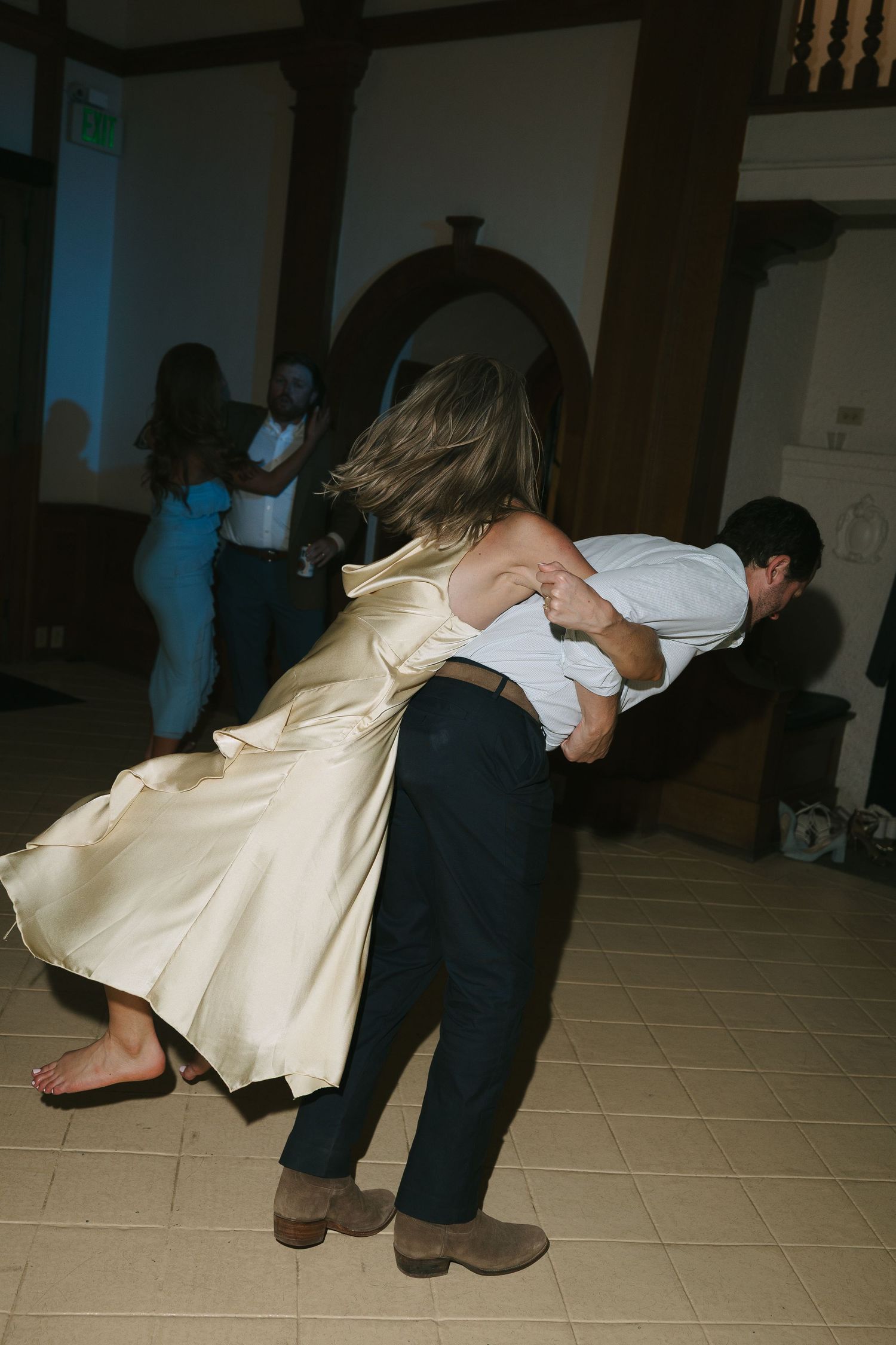 A dramatic dance dip move being performed on a tiled reception floor.