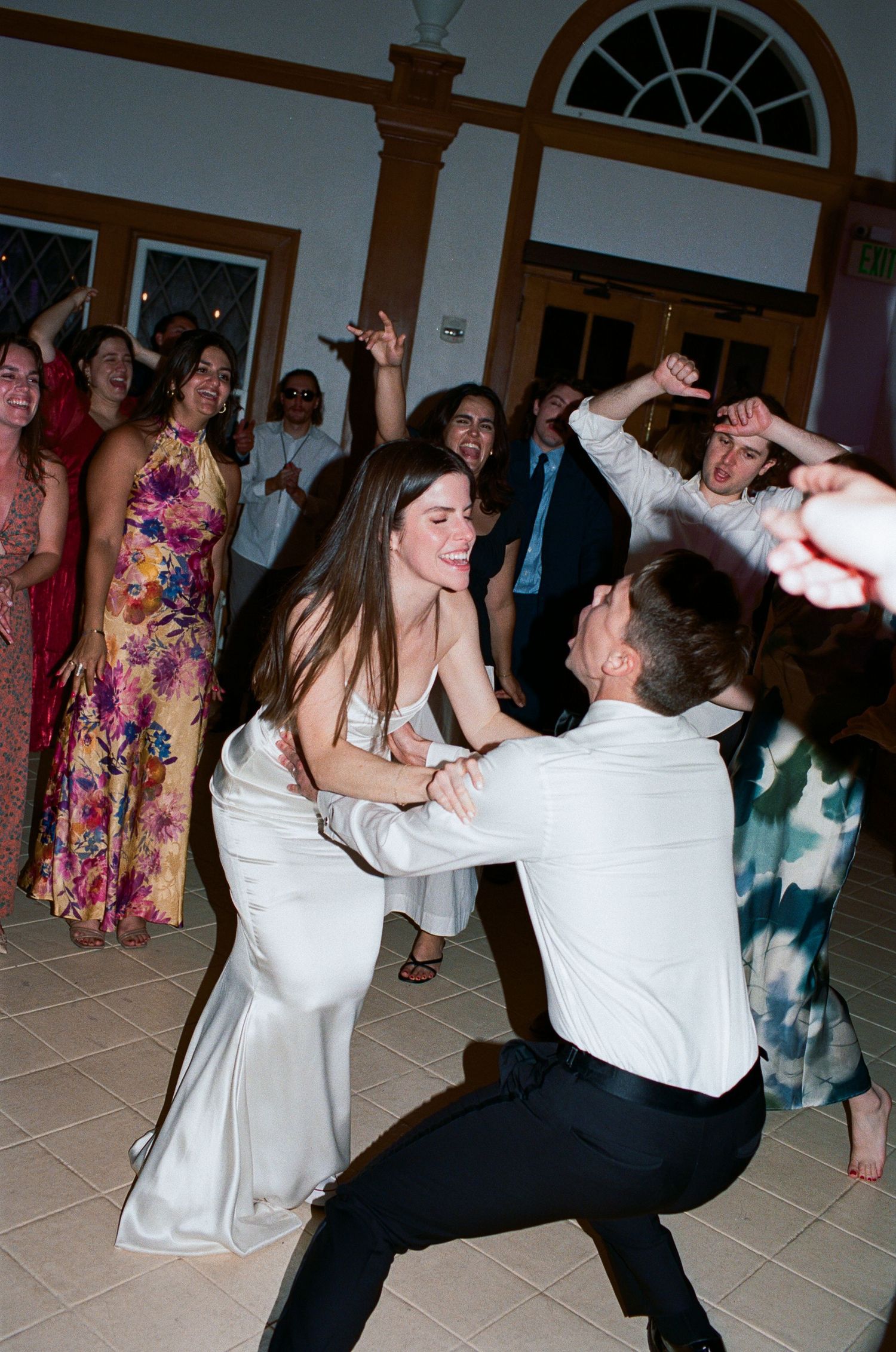 Wedding guests dancing and celebrating on the dance floor during a lively reception.
