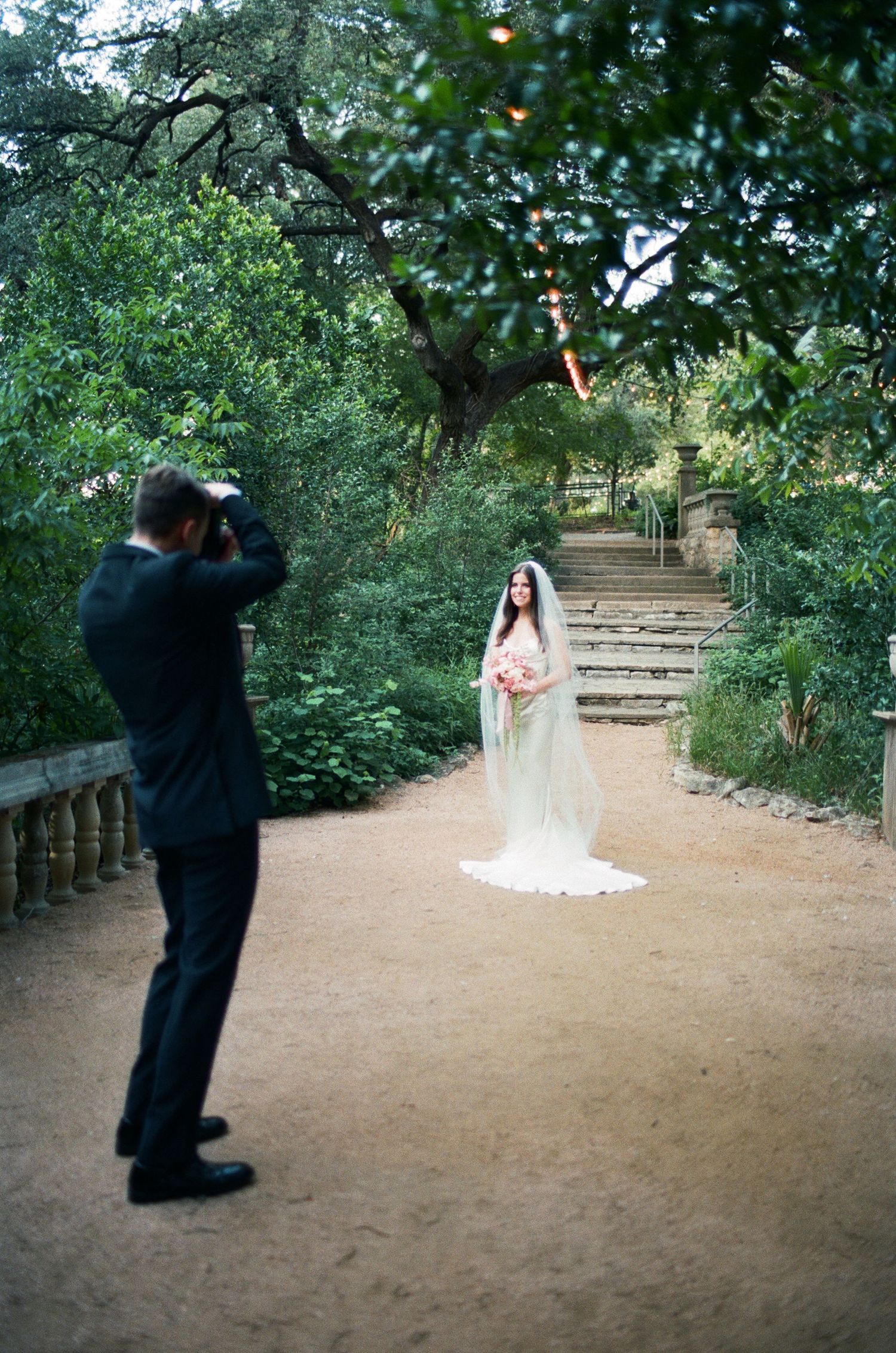 Wedding photographer captures couple on rustic garden path with stone steps.