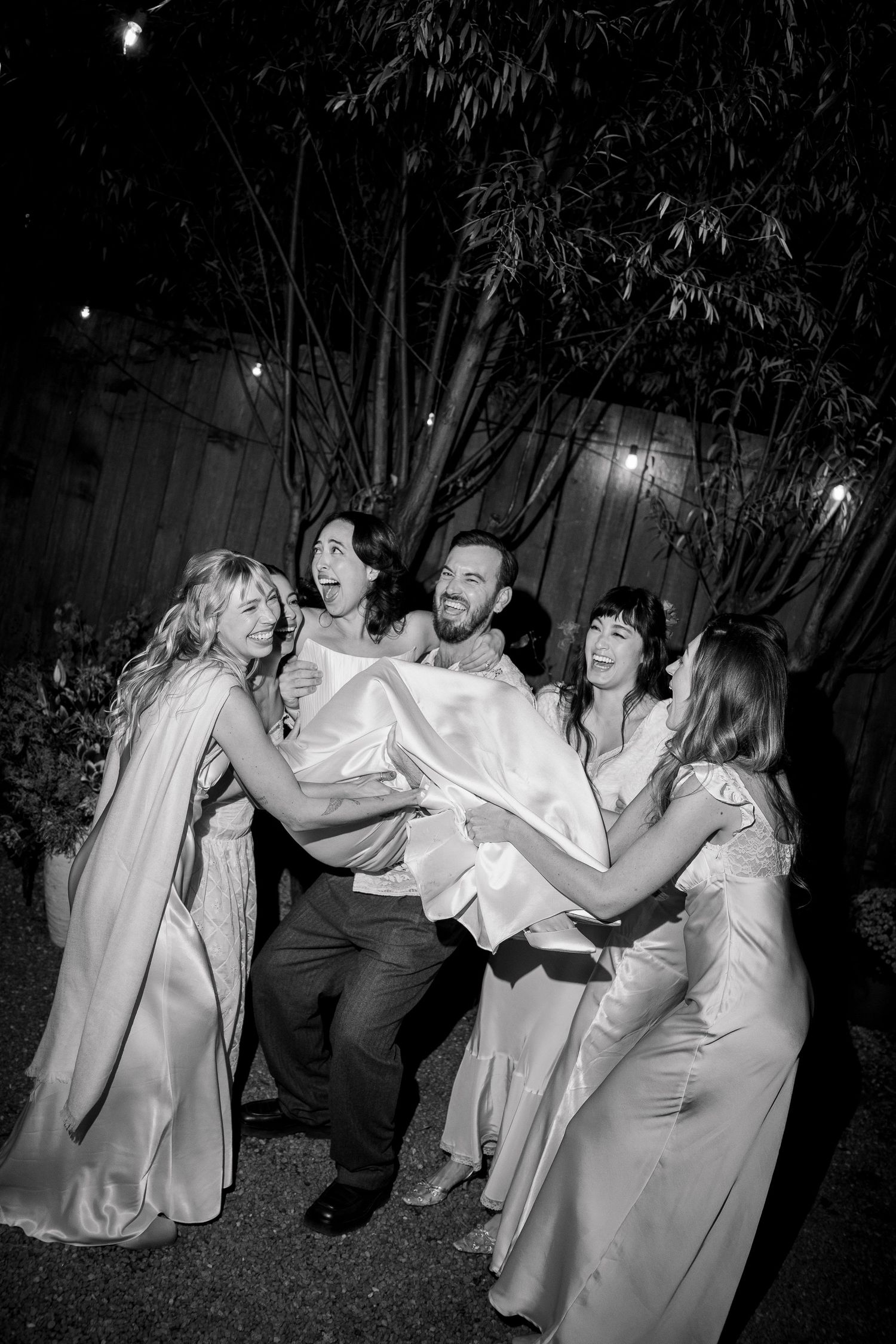 Wedding party members dance and pose together in a playful sequence of black and white nighttime photos.