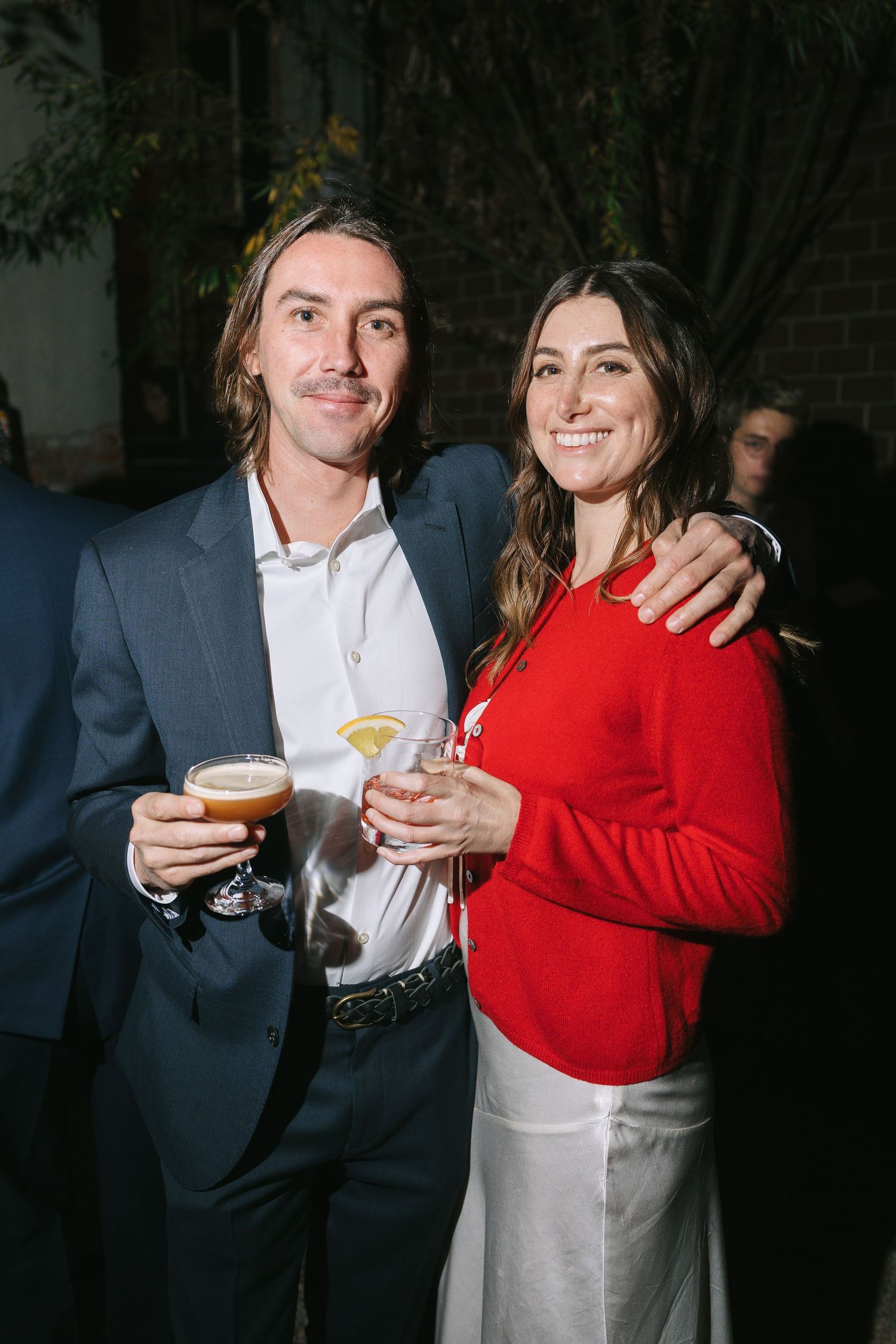 A couple in formal attire enjoying cocktails at an evening event.