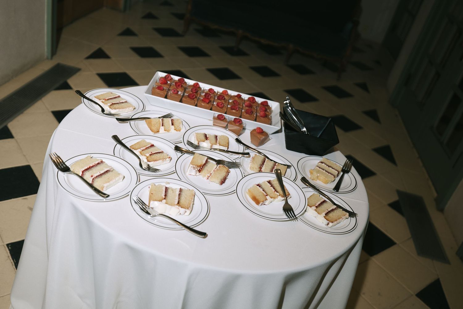 White plates and serving utensils arranged on a banquet table.