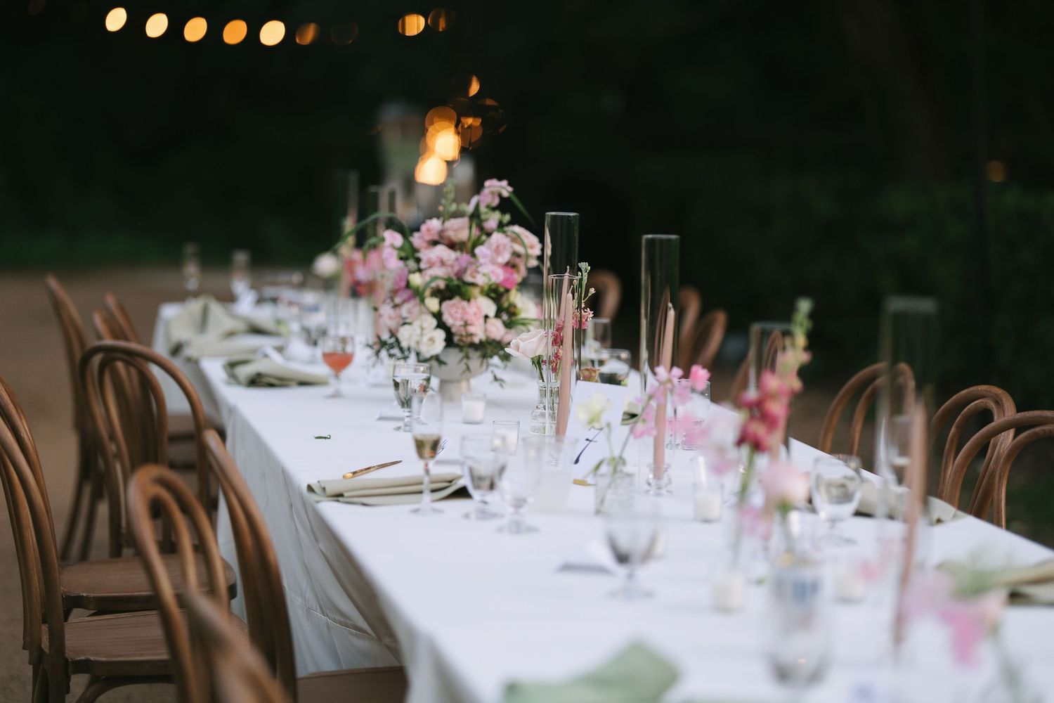 Wedding reception tables decorated with pink floral centerpieces and glowing candles.