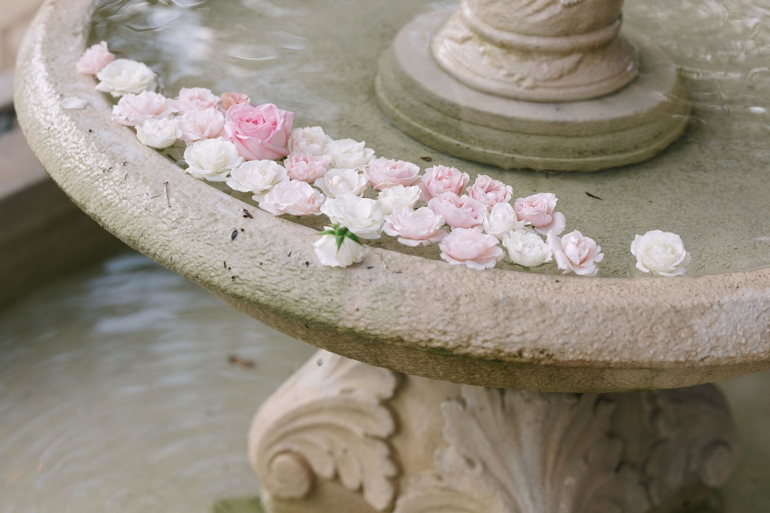 Delicate pink meringue cookies arranged on a decorative stone garden pedestal.