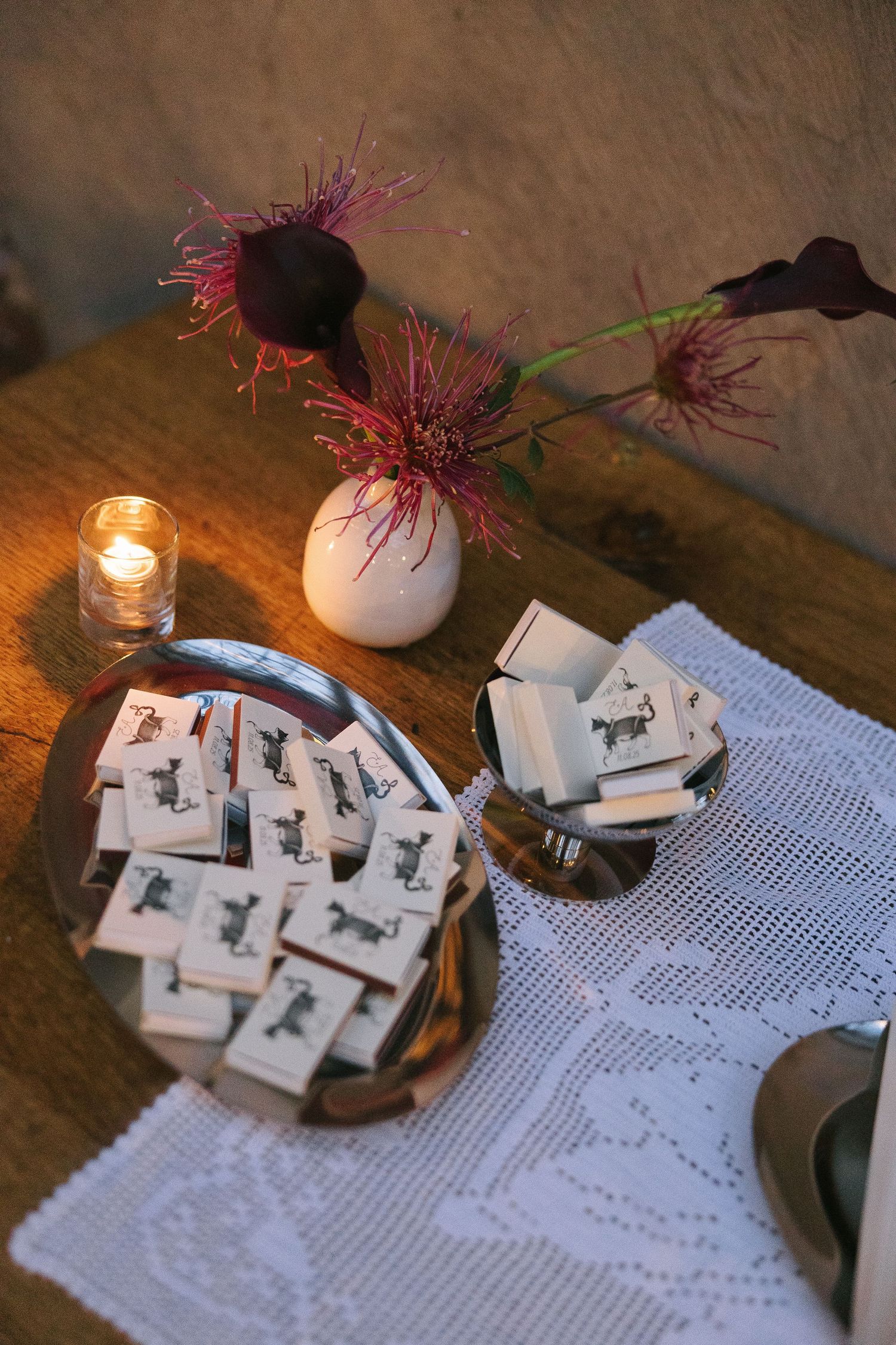 Wedding reception details featuring decorative cards on silver platters with candlelight and flowers.