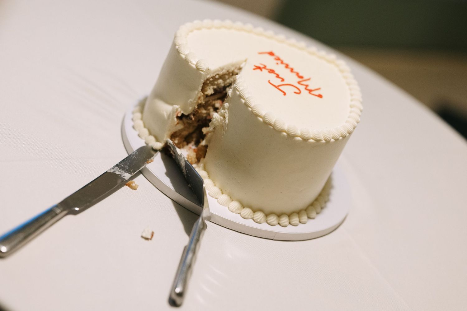 A white wedding cake with simple frosting sits ready to be cut on a table.