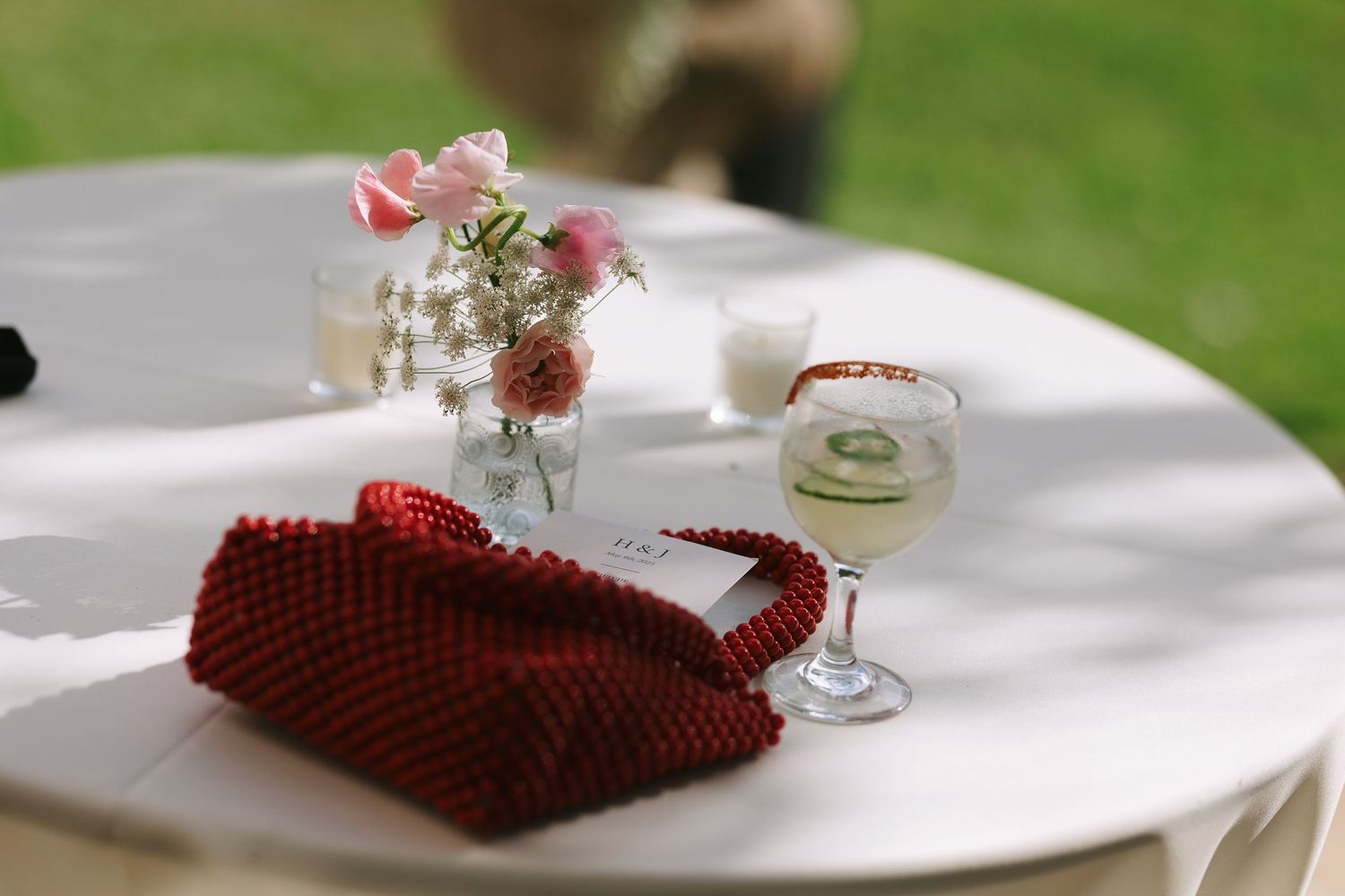 White tablecloths and red decorative elements at an outdoor reception.