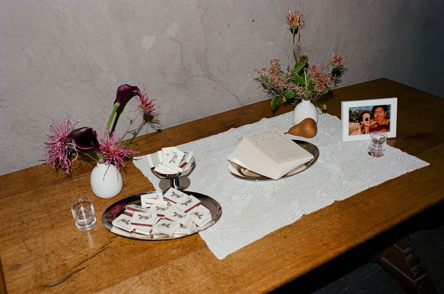 A wooden table set with white plates, glasses, and decorative elements in a rustic dining setting.