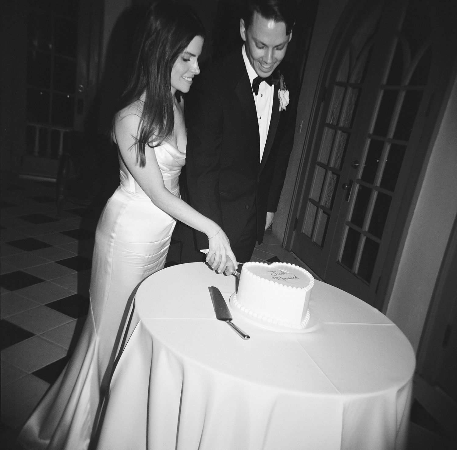 Black and white photo of a wedding cake cutting moment.