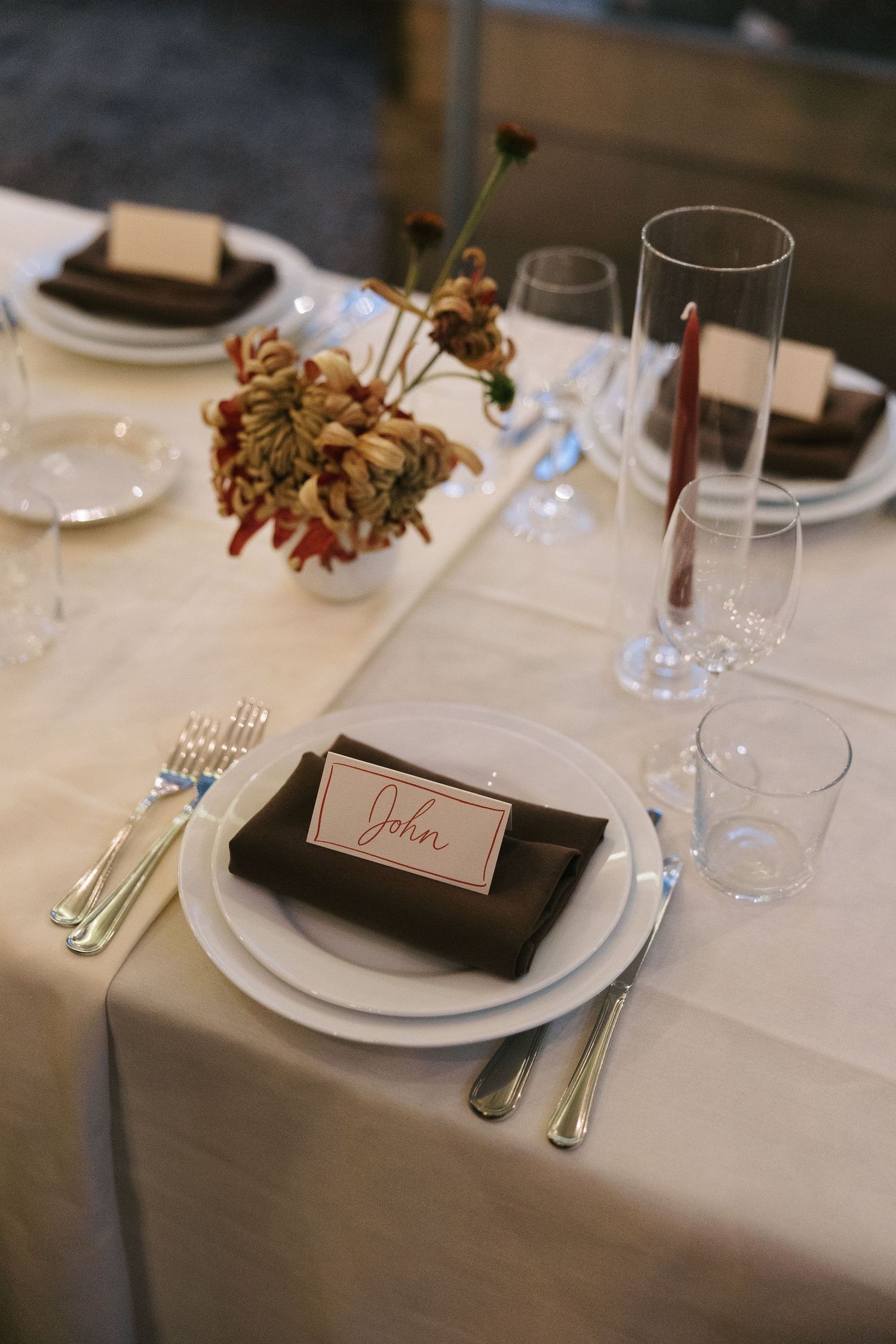 Elegant table setting with white plates, glassware and place cards for formal dining event.