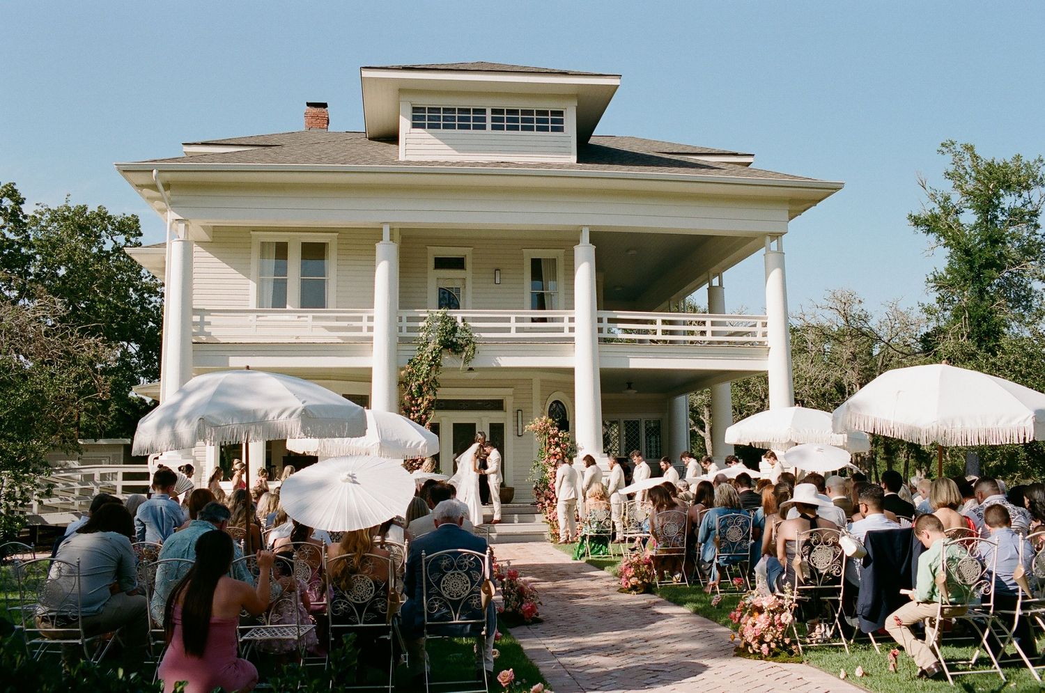 Exterior view of a classic white house with wedding celebration setup.