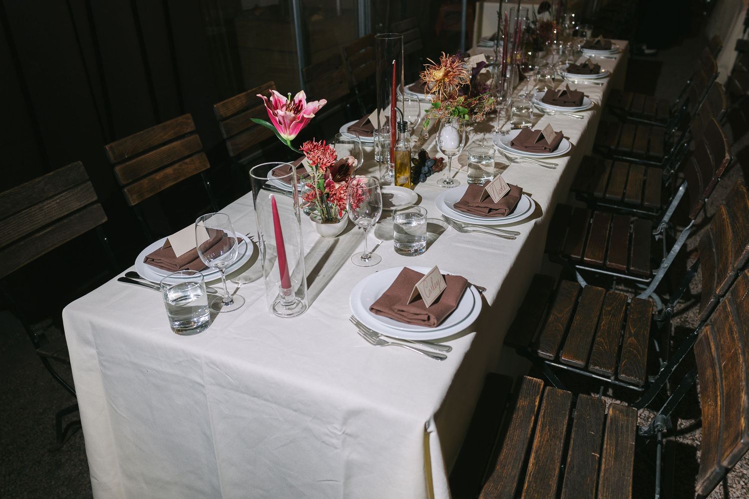 Long dining table decorated with pink floral centerpieces and white tablecloths.