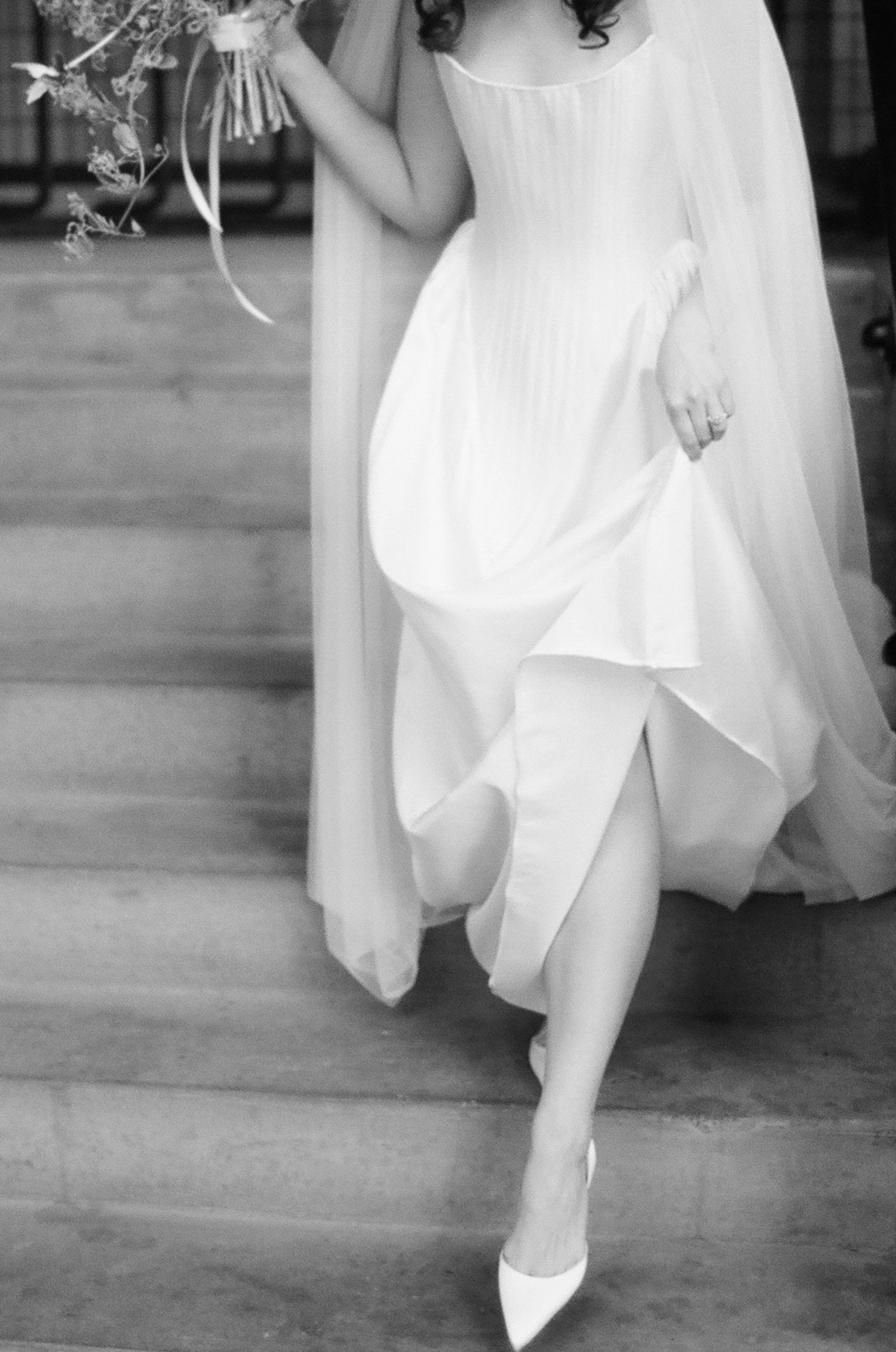 Black and white image of feet in white shoes dancing on a wooden floor, with flowing white fabric swirling above.