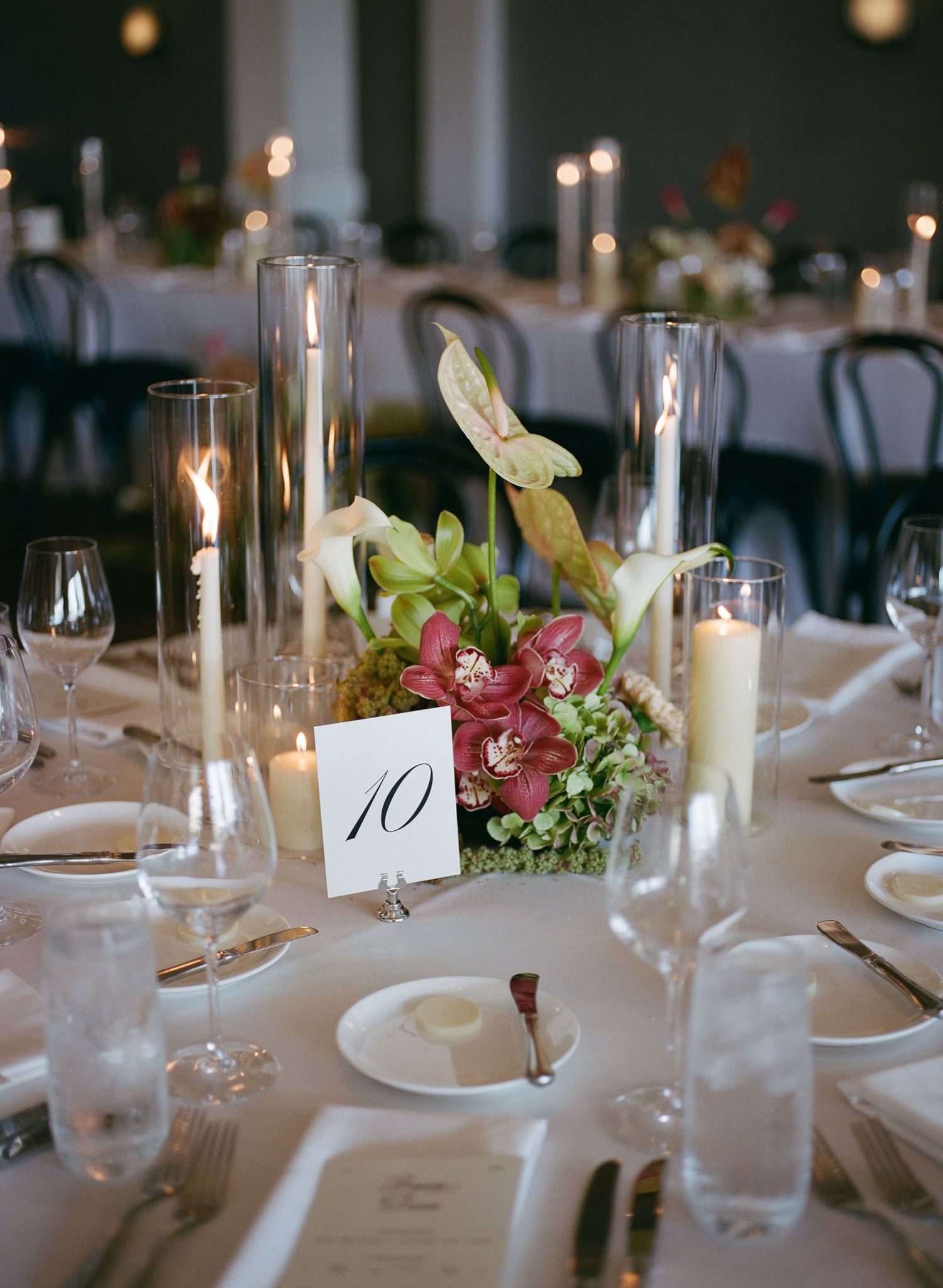 Elegant wedding reception table setting with candles, glassware and floral centerpieces.