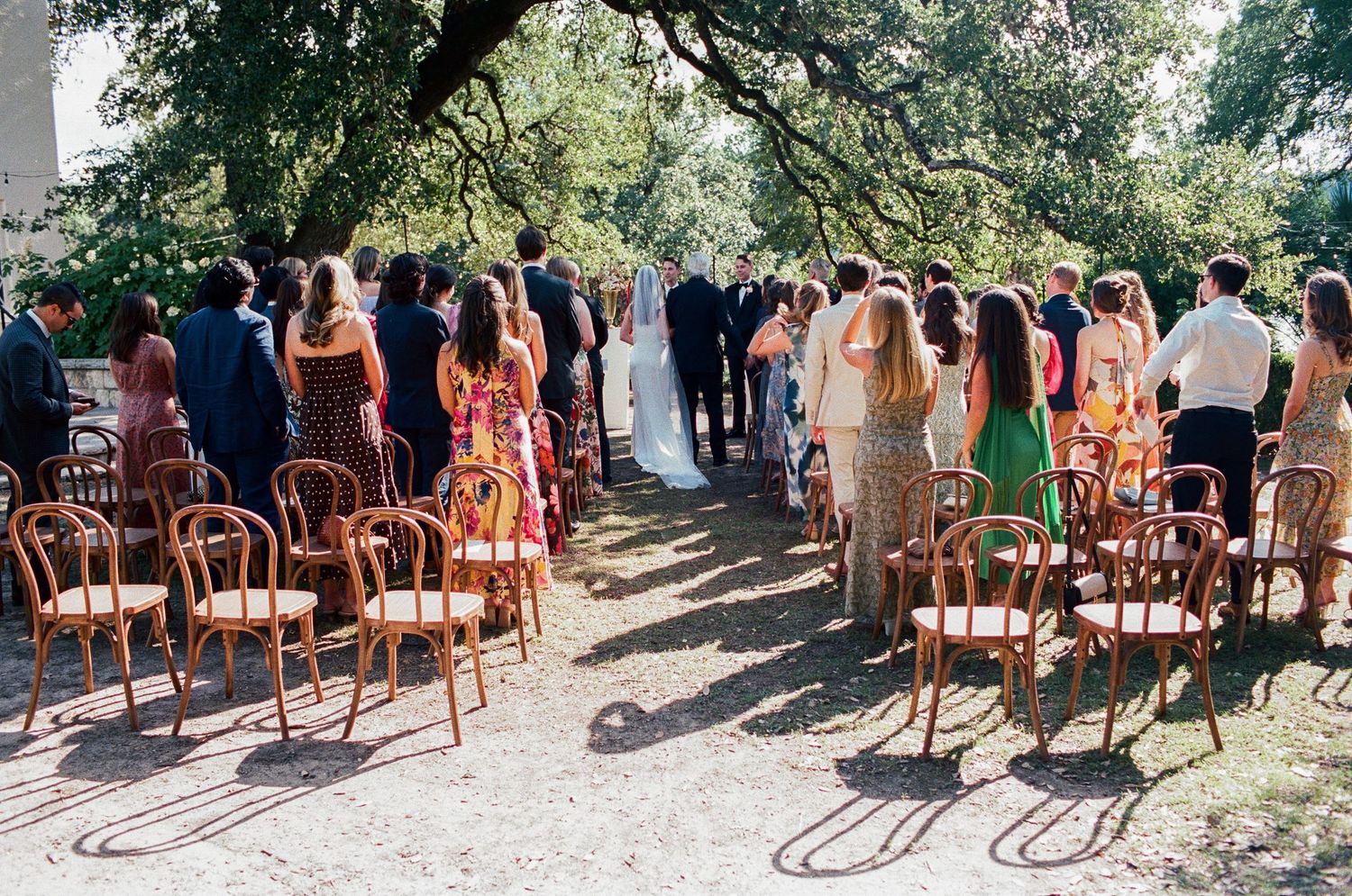 Multiple rows of empty wooden chairs set up on a lawn for an outdoor event.