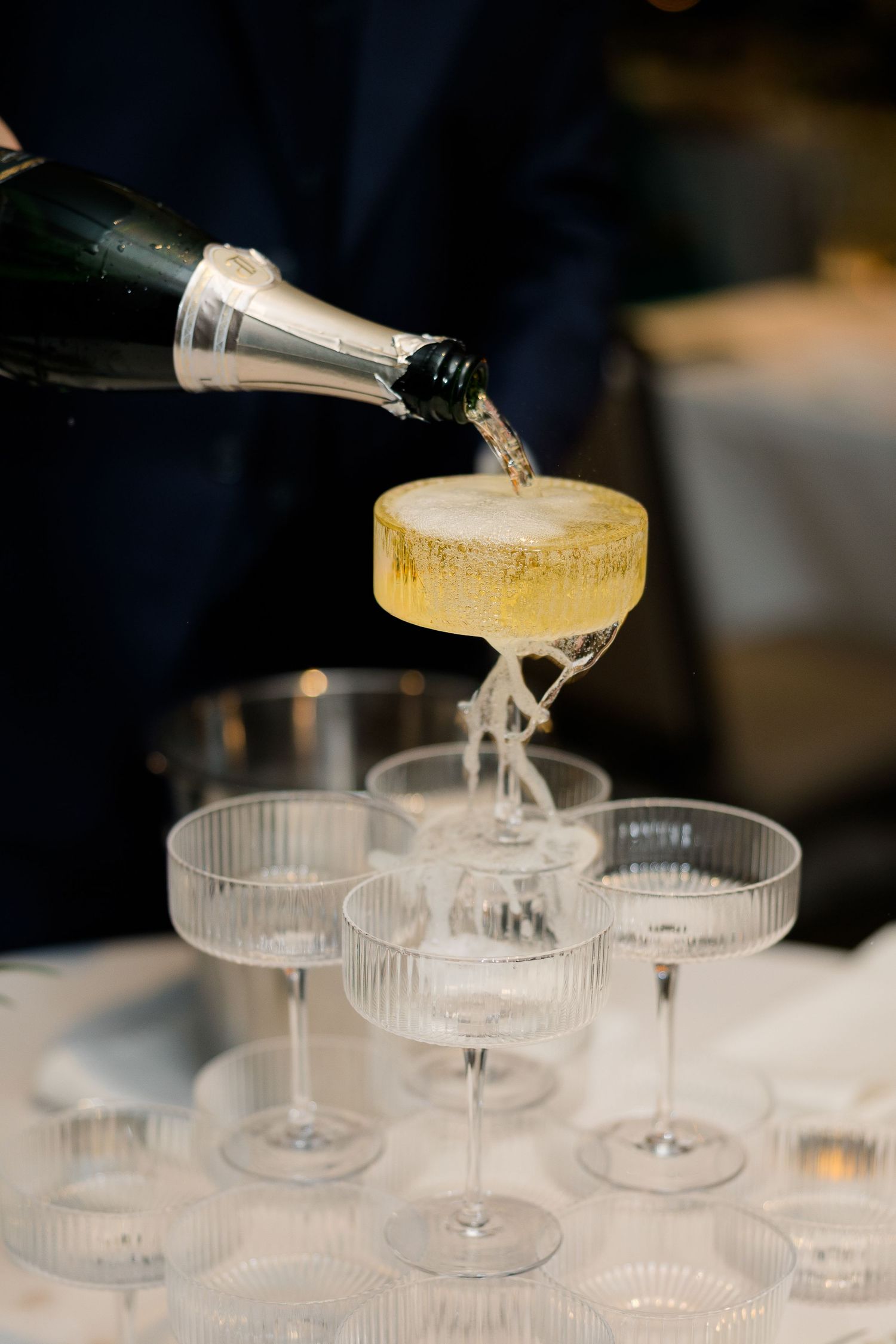 Champagne being poured into vintage coupe glasses creating a tower effect.