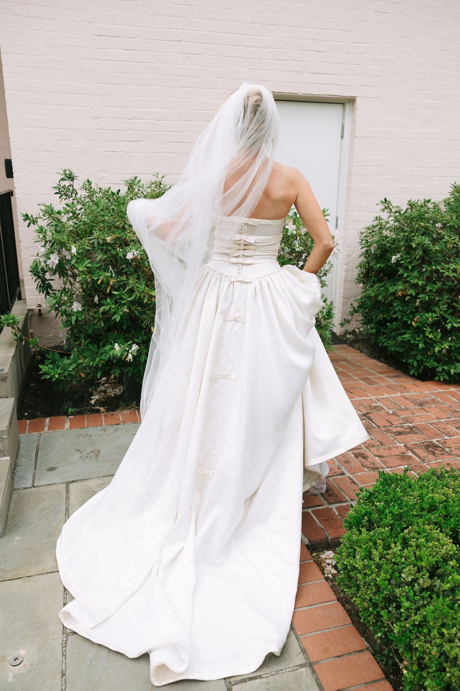A white wedding gown photographed from different angles on a brick pathway surrounded by greenery.