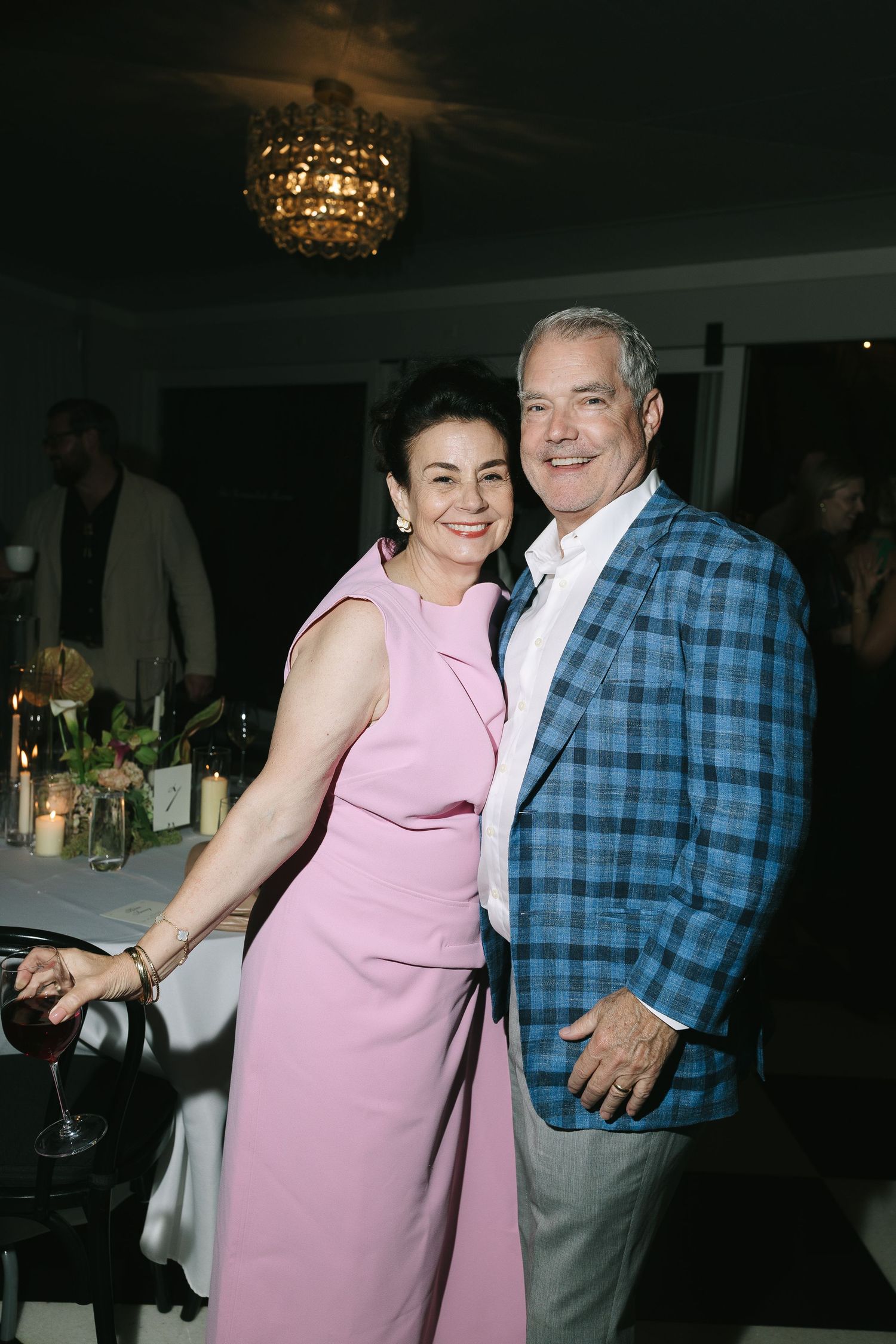 Couple dancing and laughing at a wedding reception, with the woman wearing a pink sleeveless dress.