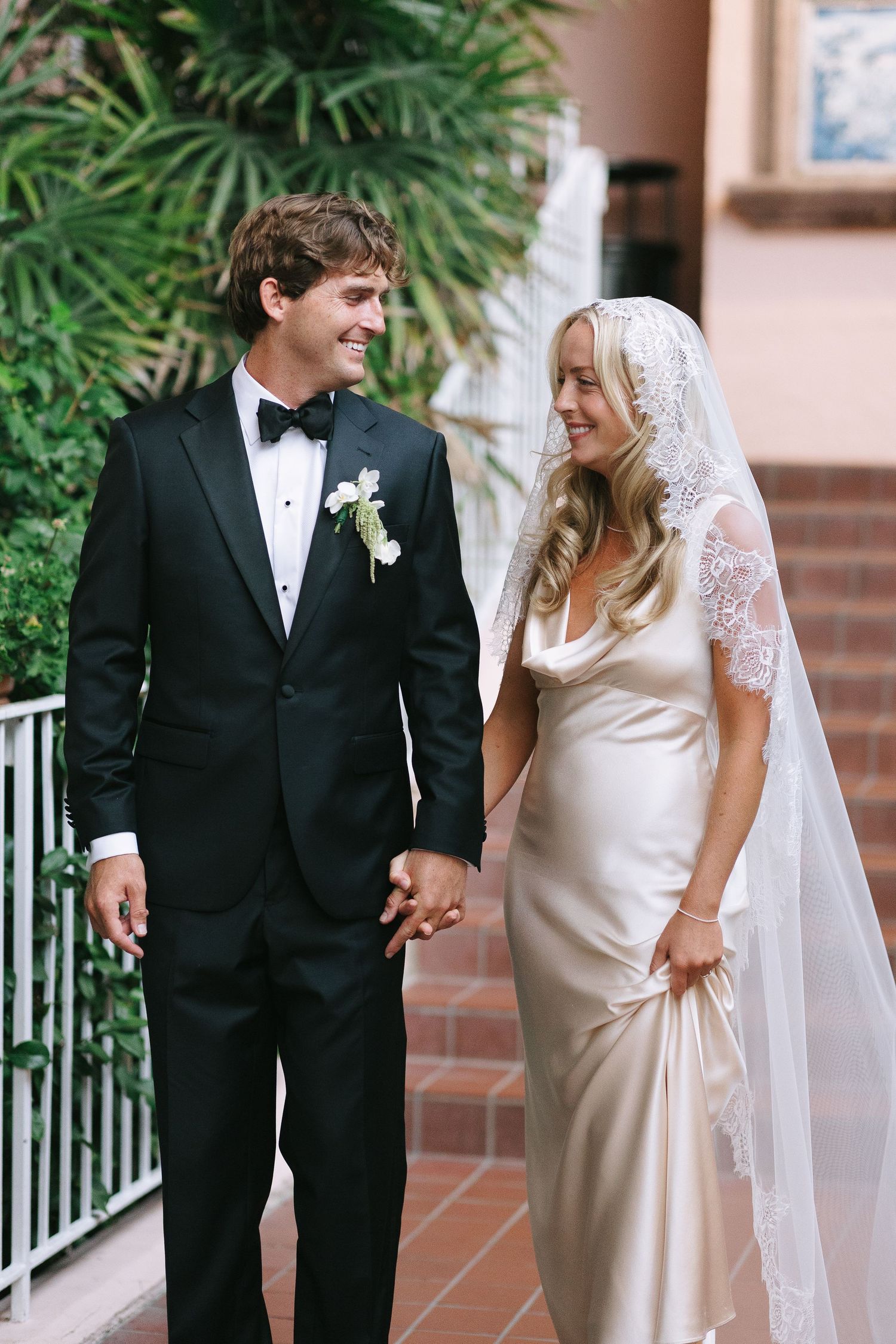 Wedding couple shares happy moment in garden setting with tropical plants.