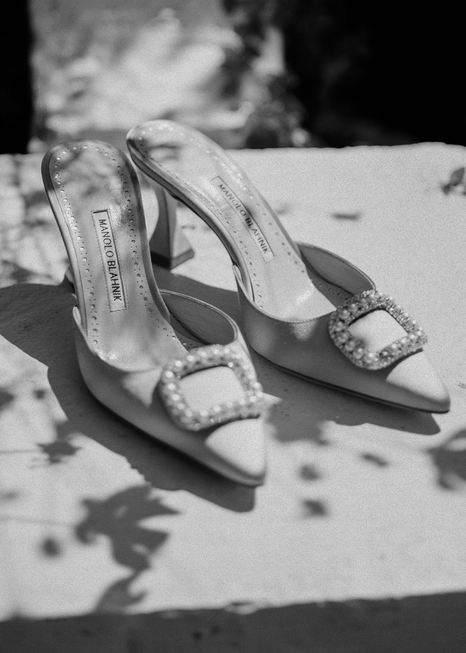 Elegant pearl-embellished bridal shoes photographed in black and white.