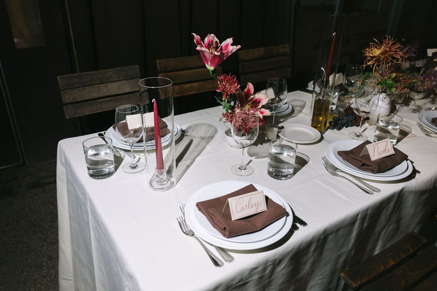 Formal dining table set with white linens, pink flowers, and elegant place settings.