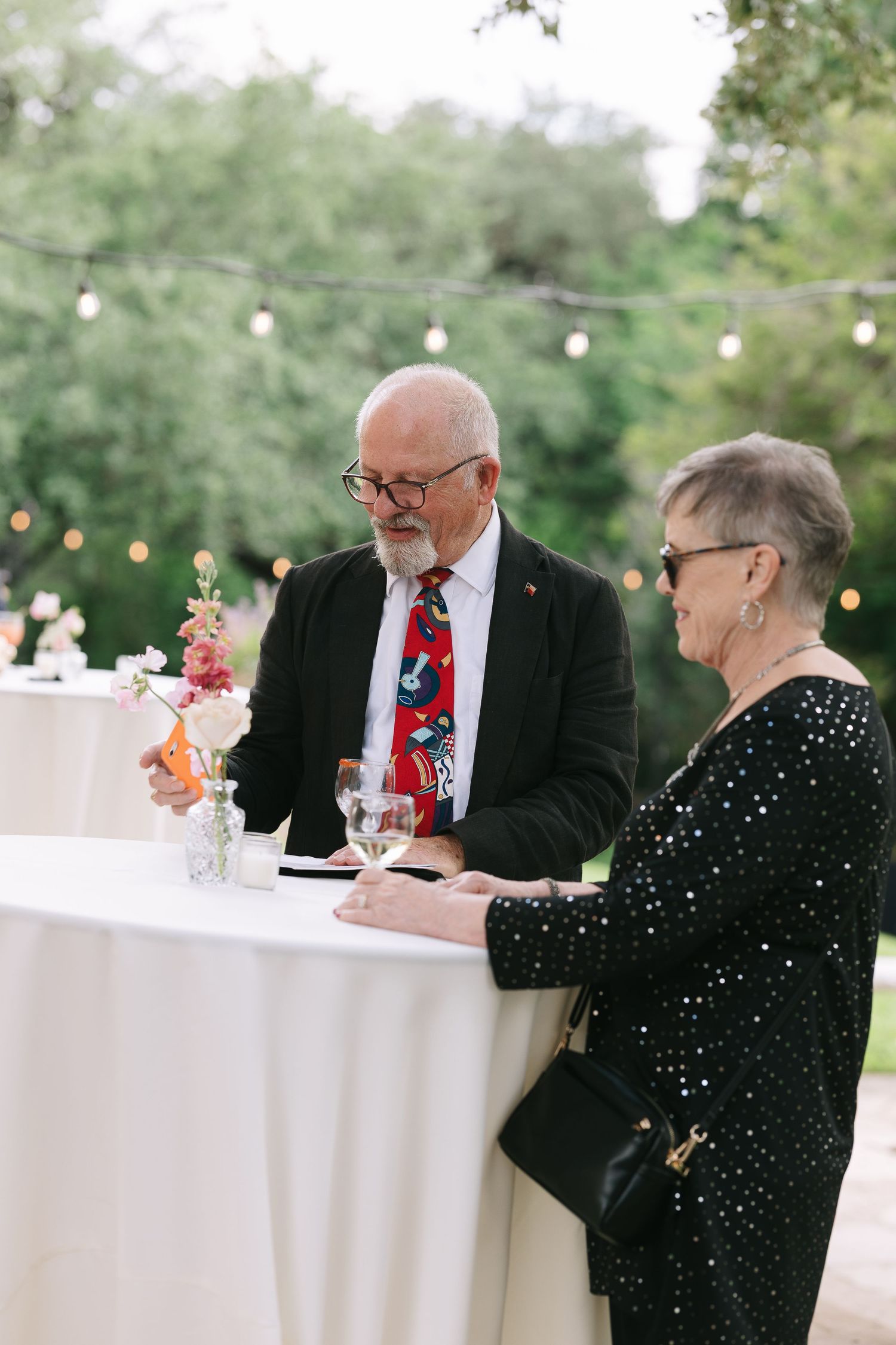 Guests enjoy conversation at round cocktail tables during an outdoor evening reception.