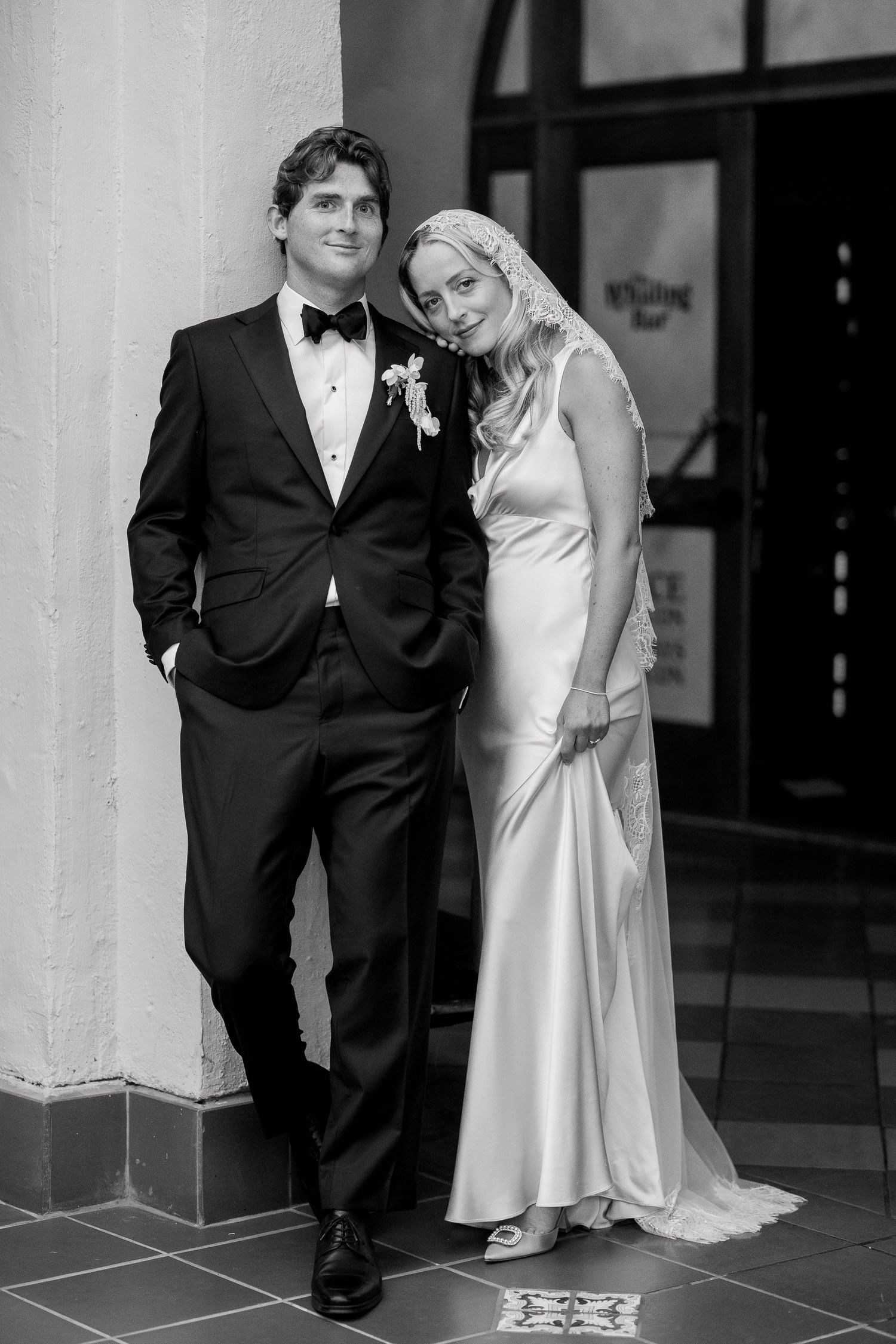 Elegant black and white wedding portrait against a modern architectural backdrop.