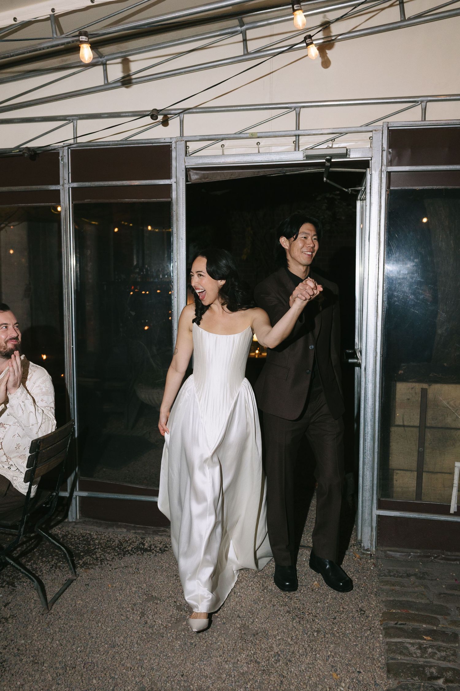 Guests in white and black attire dancing in a modern venue with industrial ceiling.
