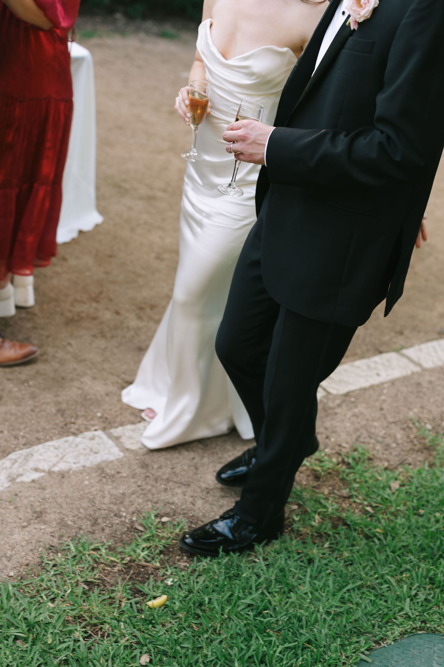 Formal attire details showing white dress and black suit at an outdoor event.