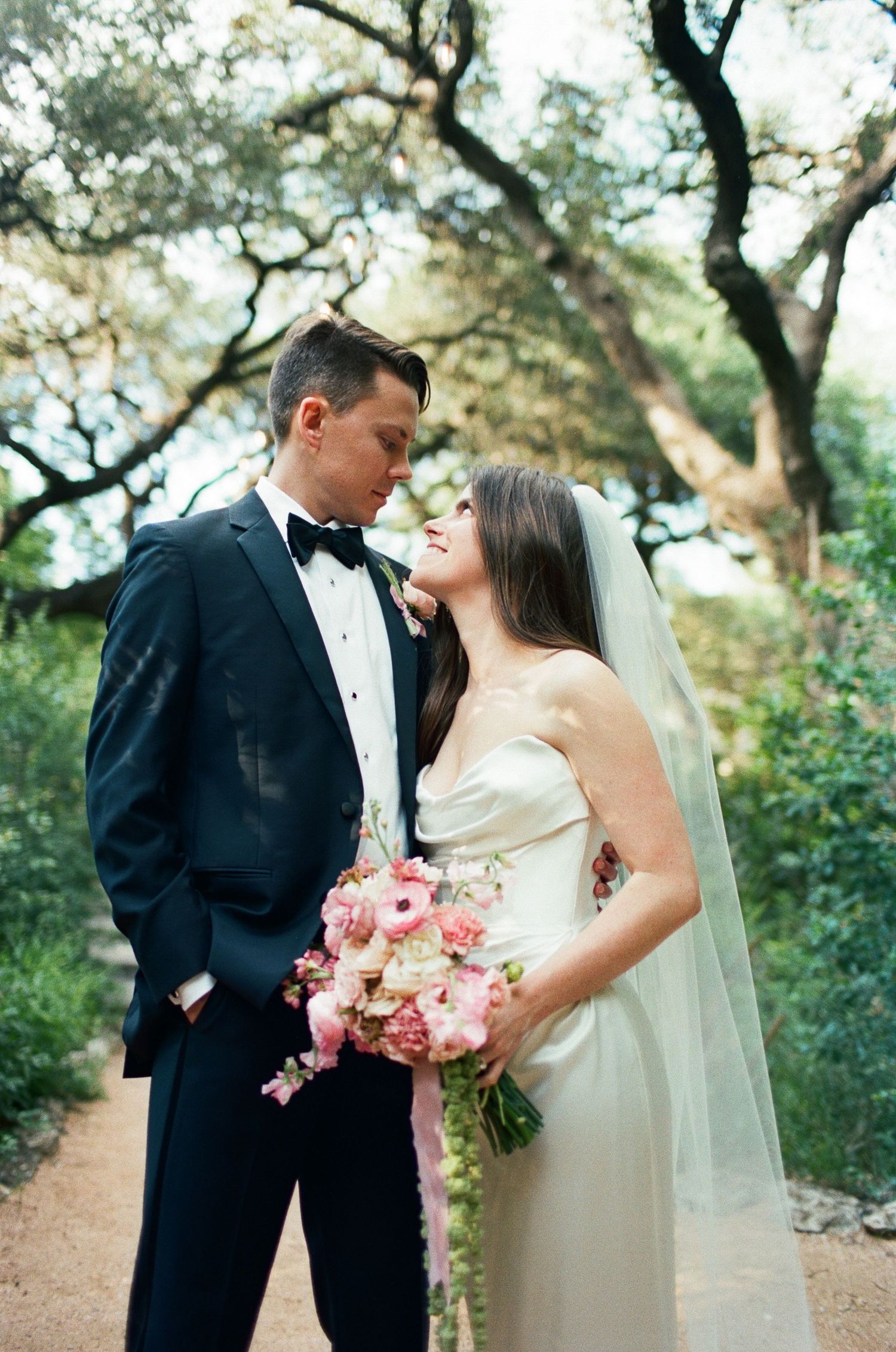 Intimate wedding portrait on garden path with classic black and white attire.