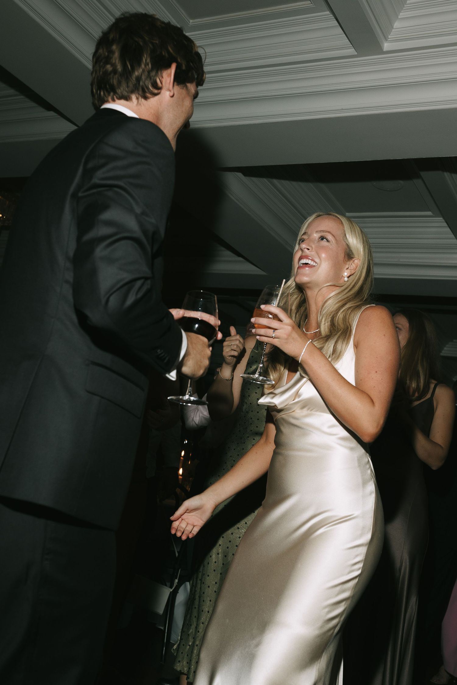 Wedding reception dance floor scene with guests celebrating in formal attire under dim lighting.