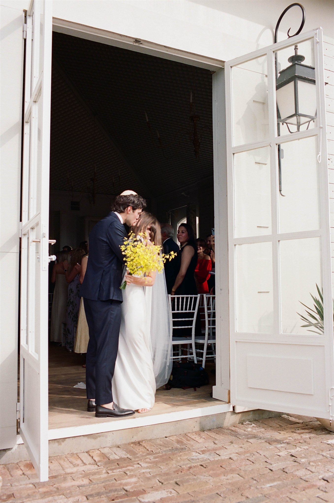 White French doors open to reveal a wedding ceremony space with guests gathered inside.