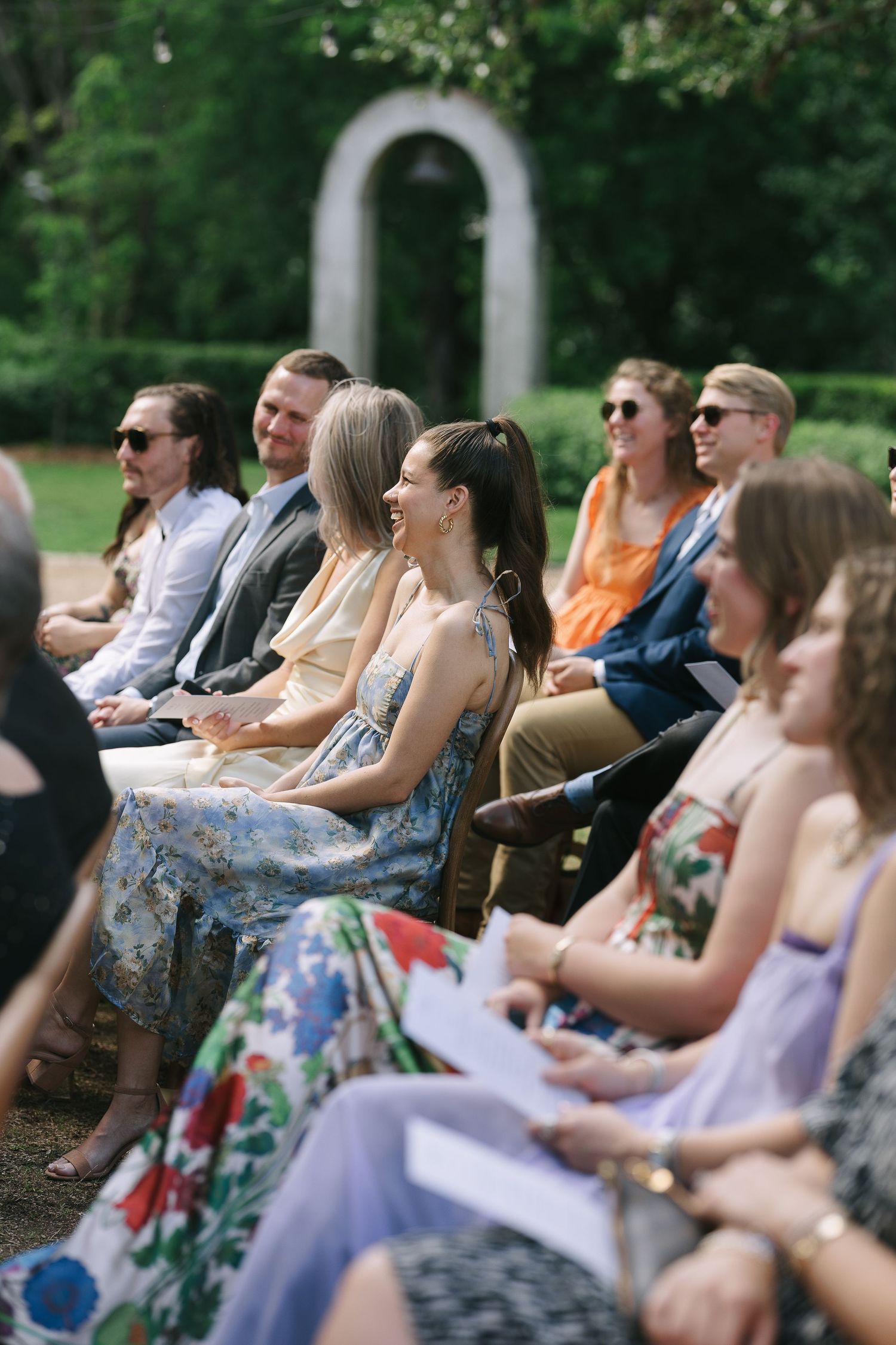 Wedding guests in colorful summer attire seated for outdoor ceremony.