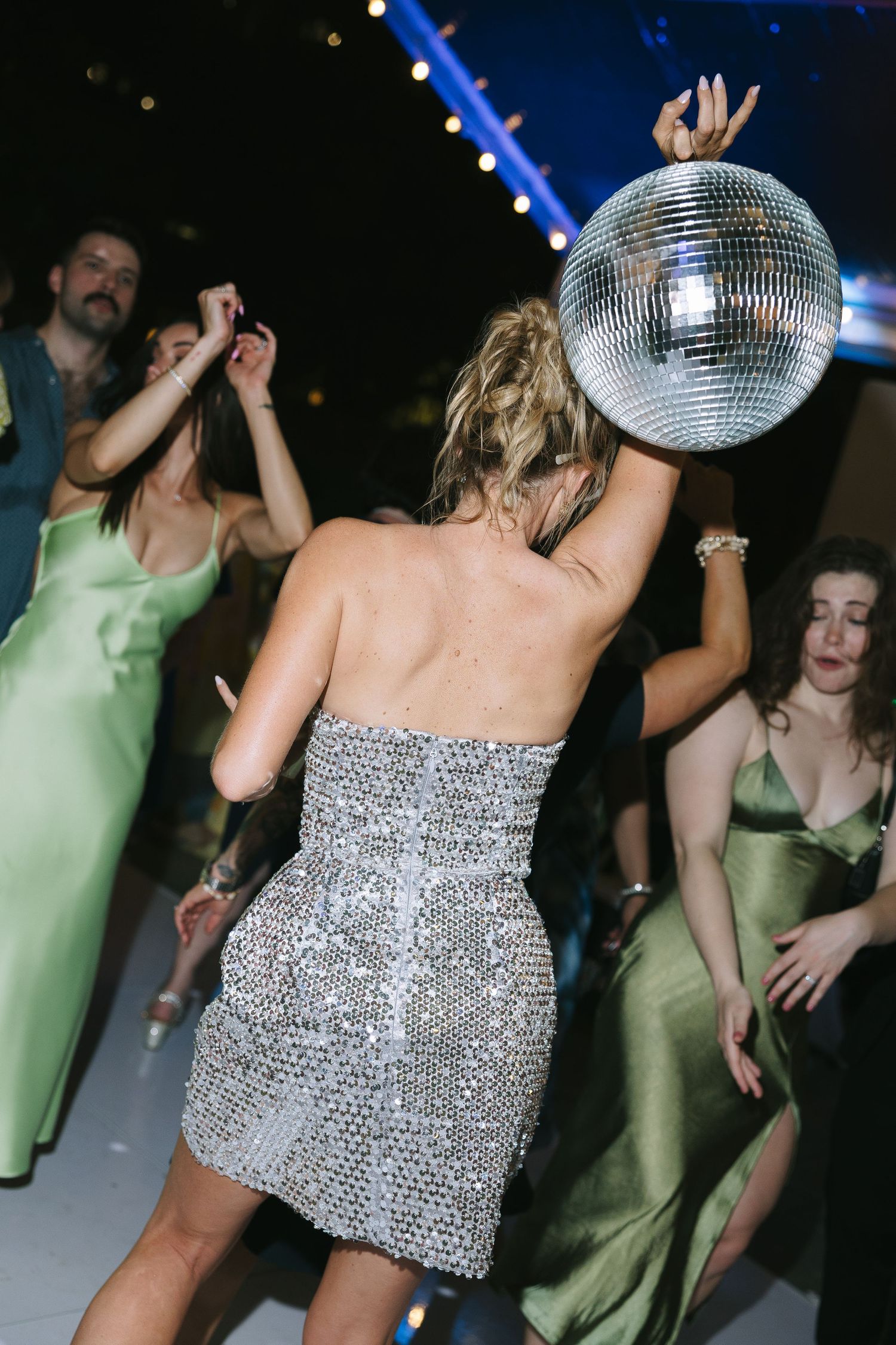 Dance party scene with disco ball and person in sparkly dress.