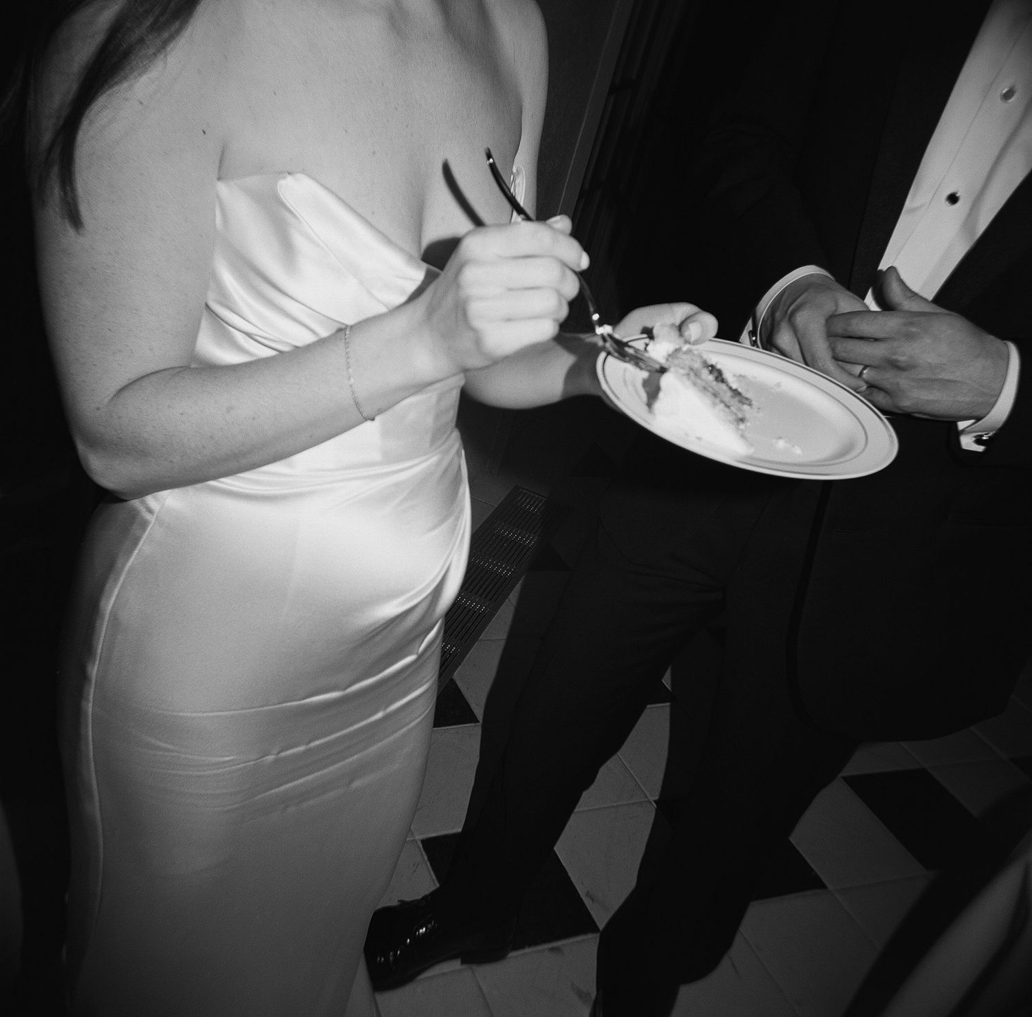 Black and white detail shot of formal wedding attire at a reception.