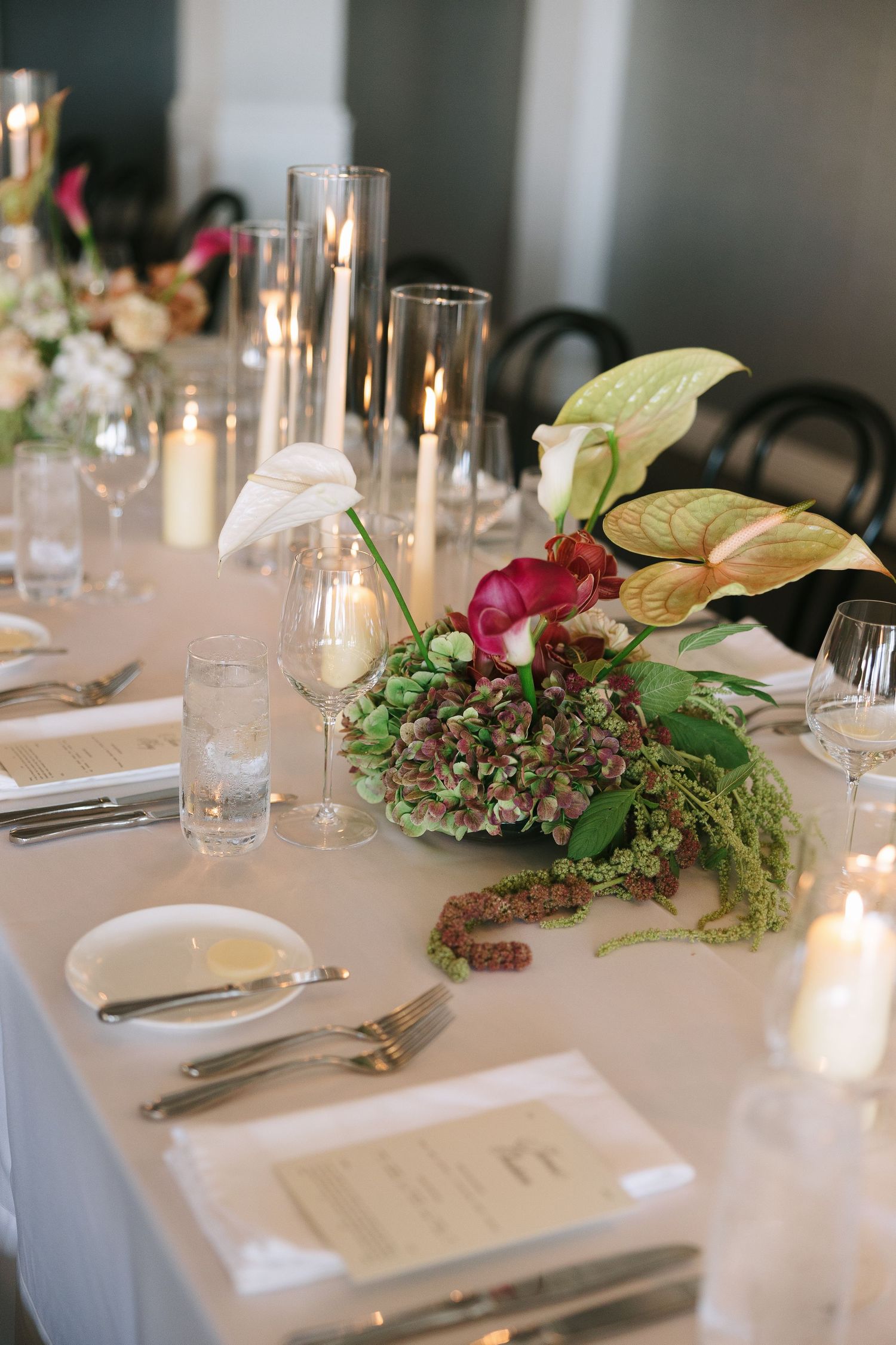 Close-up of wedding table decorations with anthurium flowers and greenery.