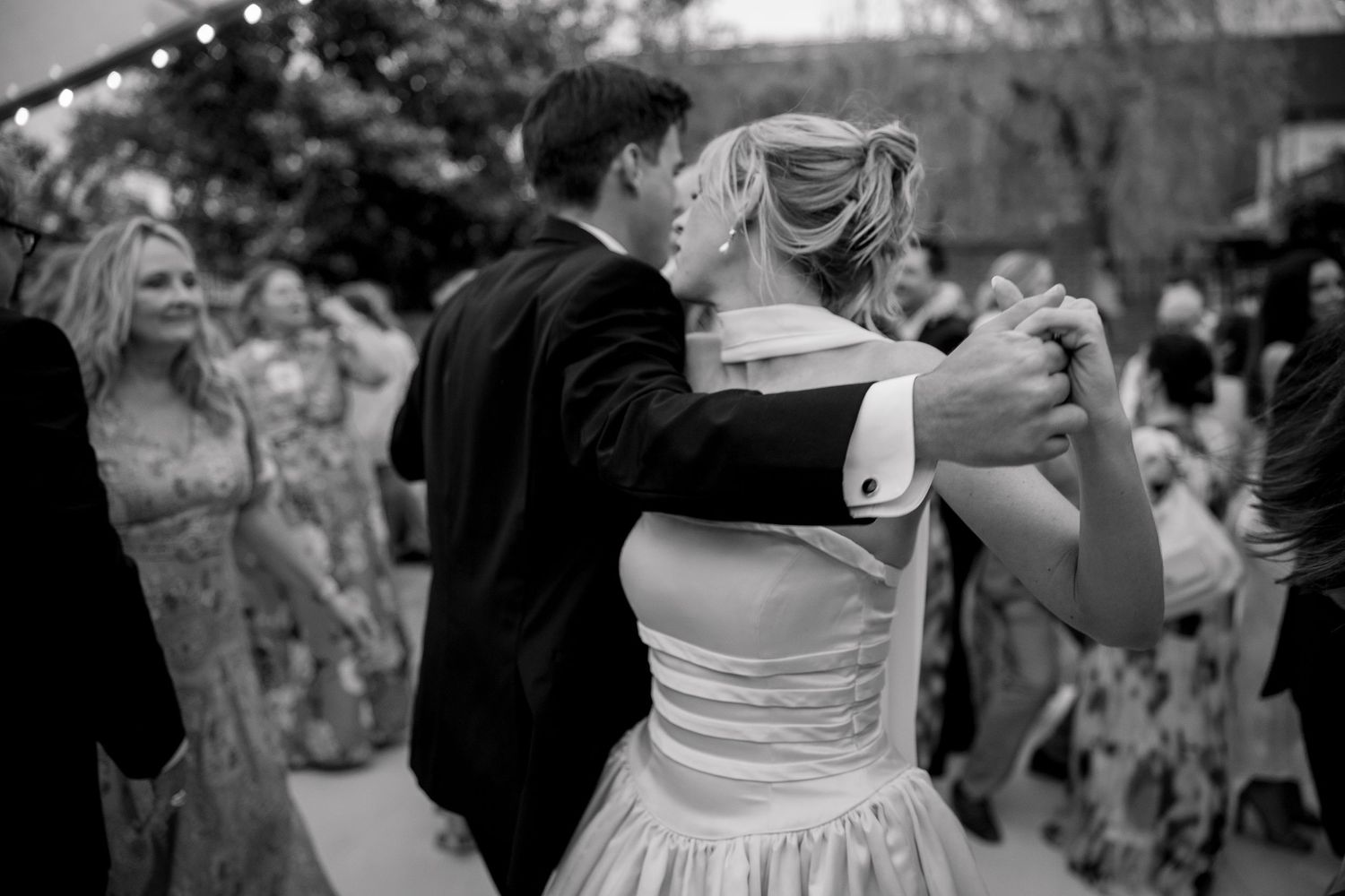 Black and white shot of dancers in formal wear at a wedding reception.