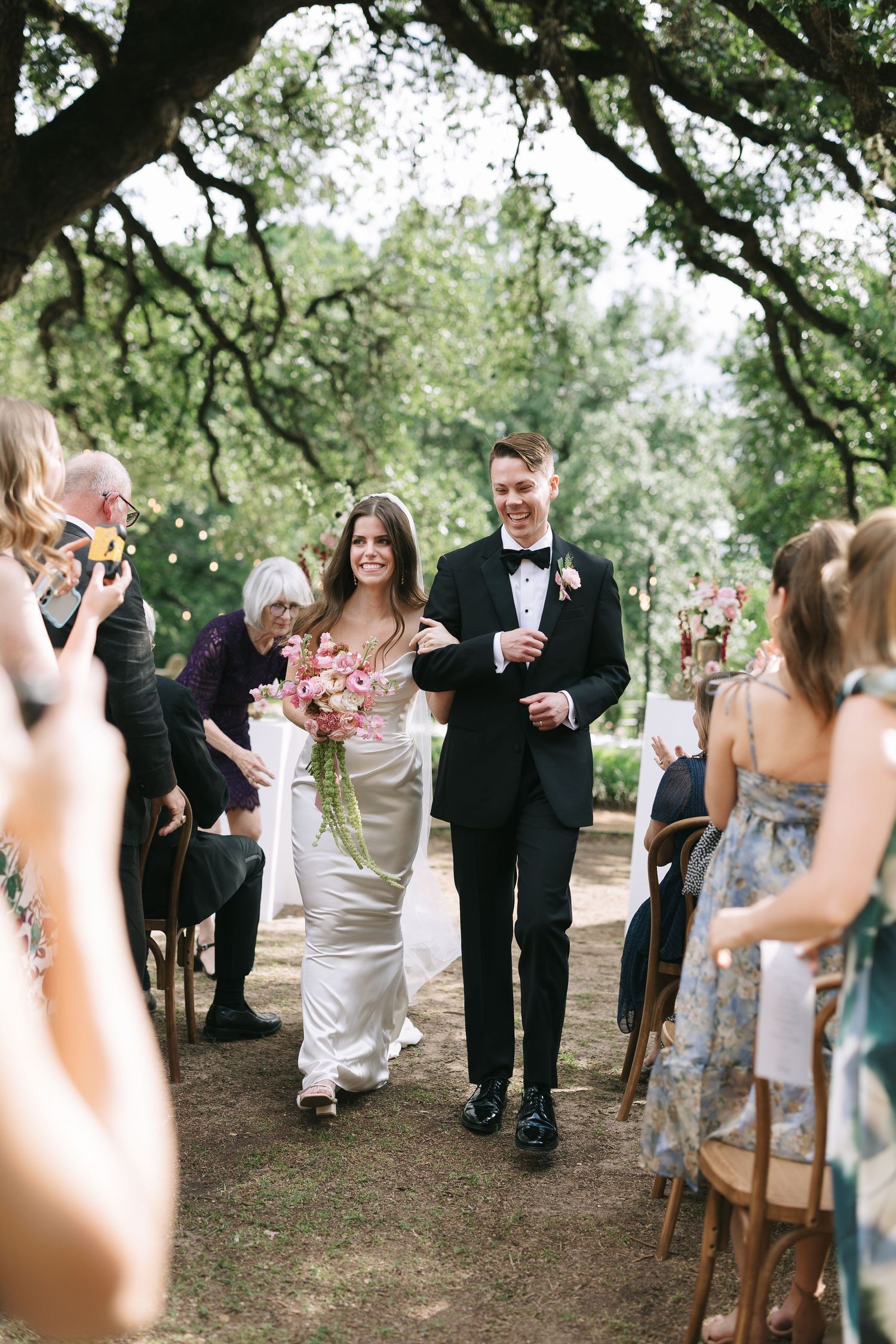 Candid moments during an outdoor wedding ceremony with guests seated on rustic wooden chairs.