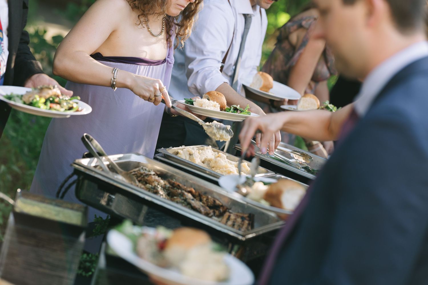 Guests enjoying plated meals at an outdoor wedding reception.