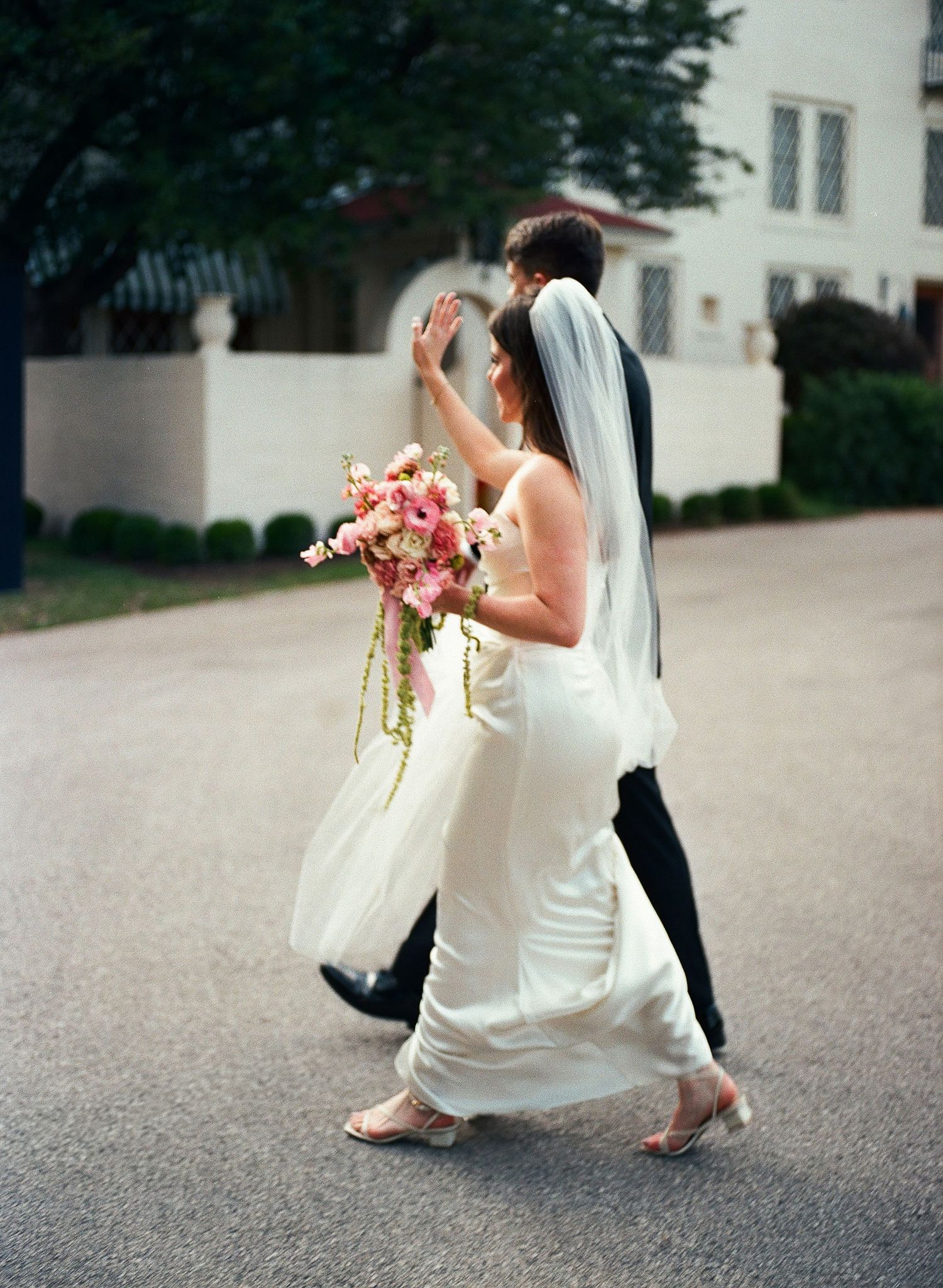 Blurred motion shot of wedding party walking outdoors with flowing dresses.