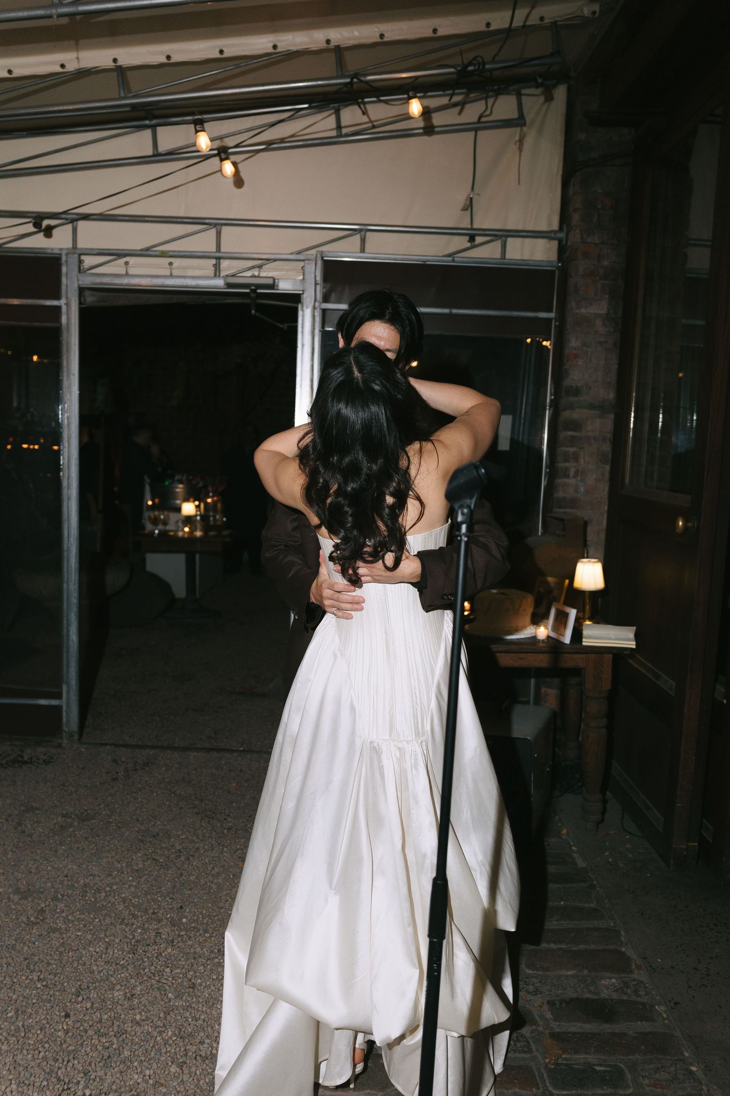 Guests in white clothing dancing and moving through an industrial-style venue.