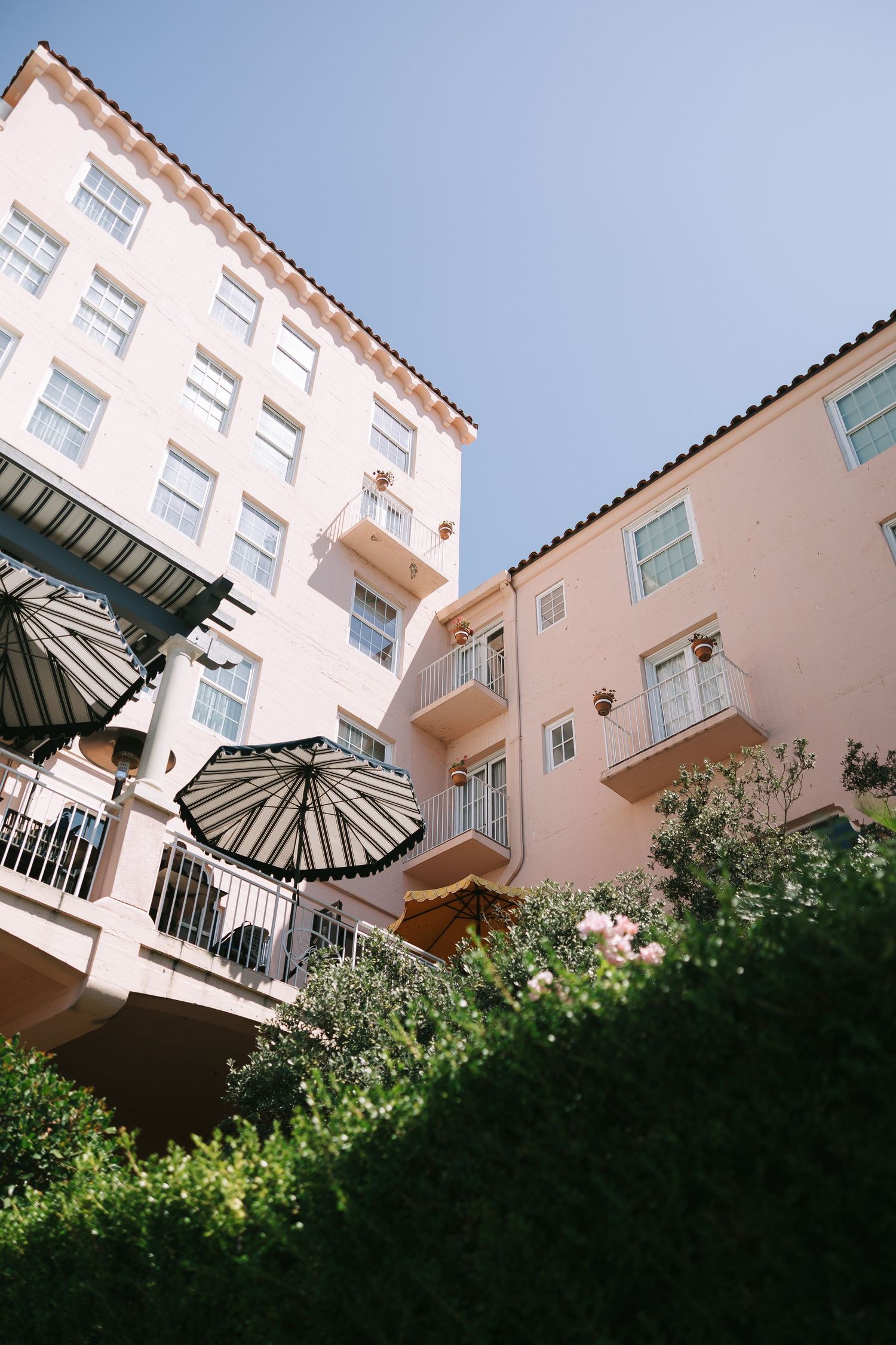 Pink Spanish-style hotel building with white balconies against blue sky.