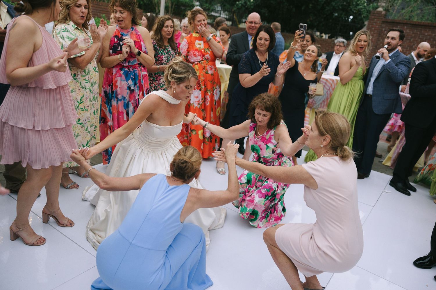 Guests enjoying themselves on a white dance floor at an outdoor wedding reception.