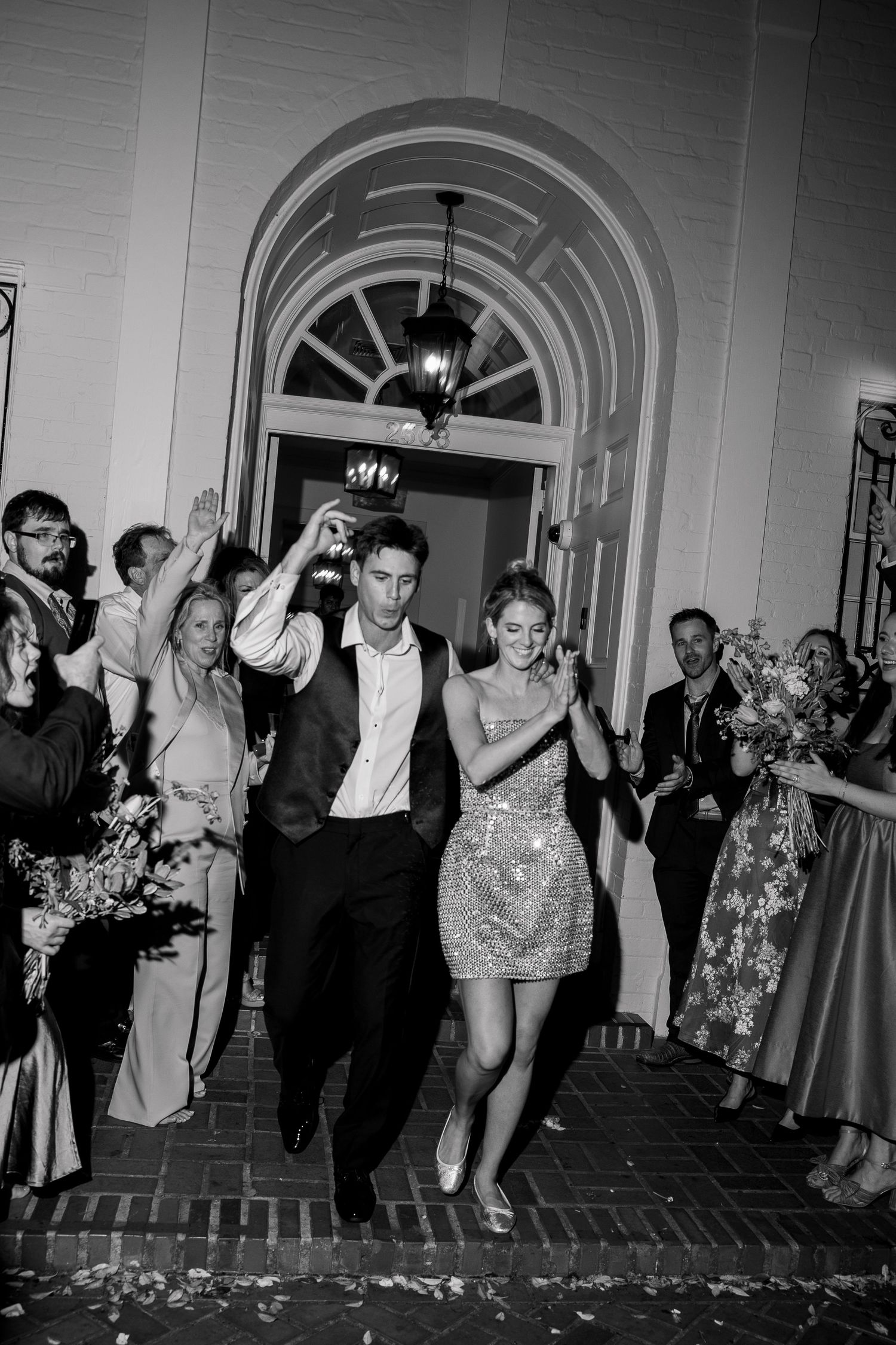 A celebratory exit through an elegant arched hallway with guests cheering.