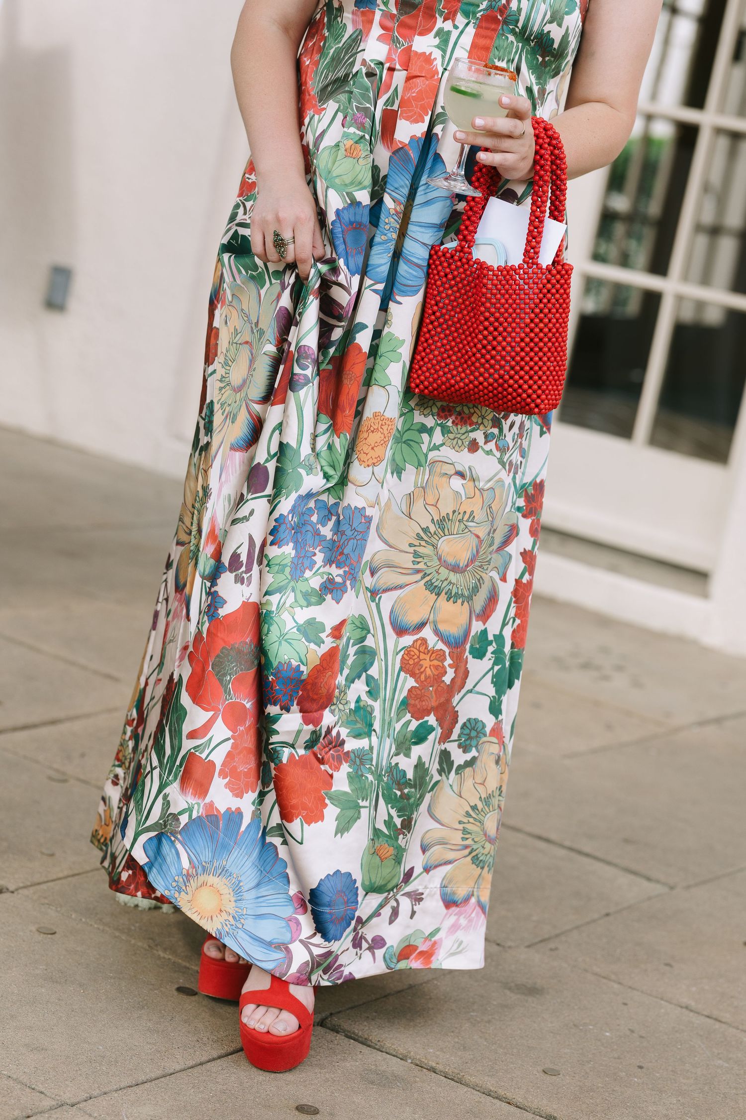 Detail shot of a floral dress paired with red accessories and shoes.