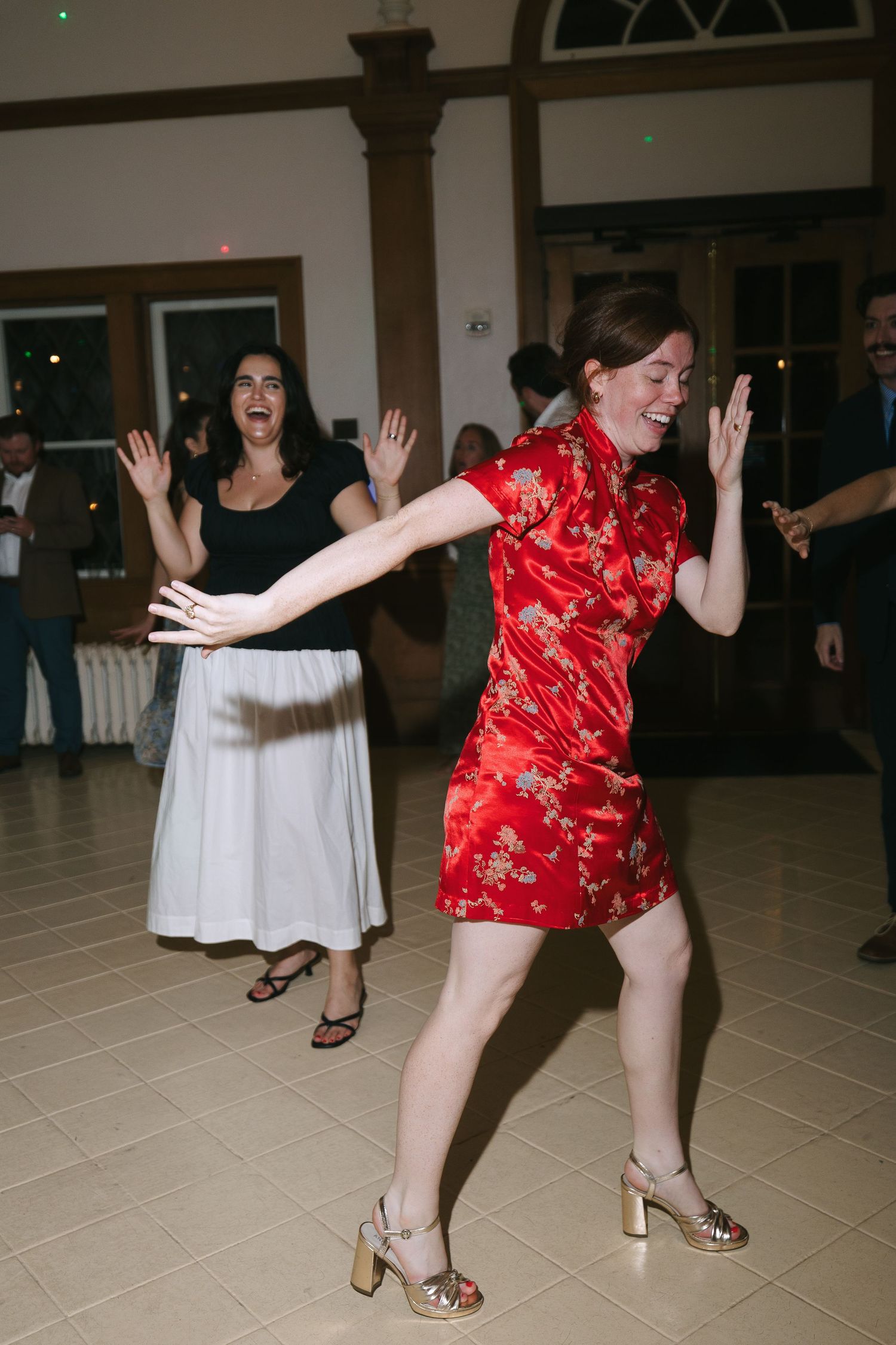 Guests dancing enthusiastically in red and white outfits on a light colored dance floor.