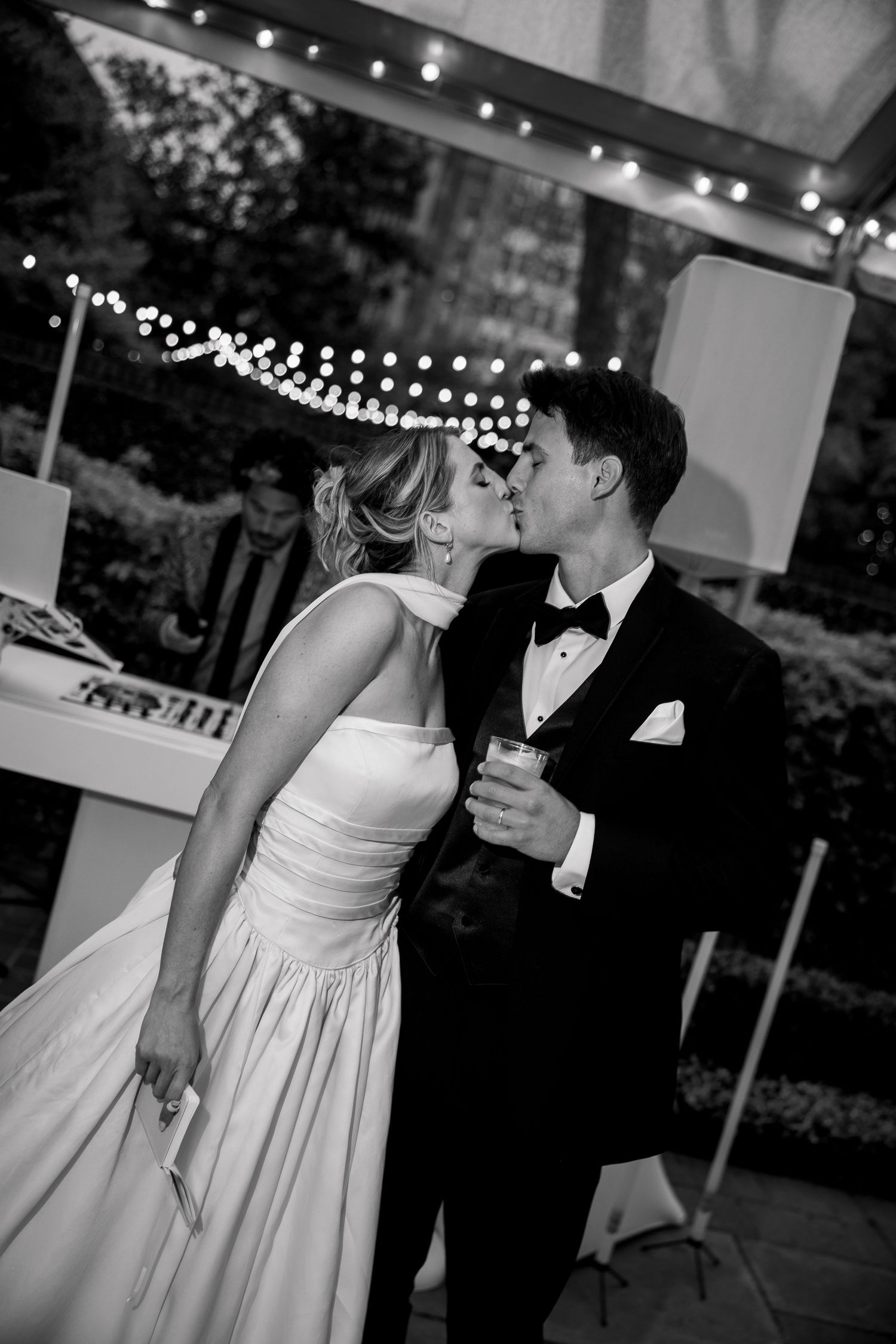 An intimate dance moment at a wedding reception illuminated by string lights.