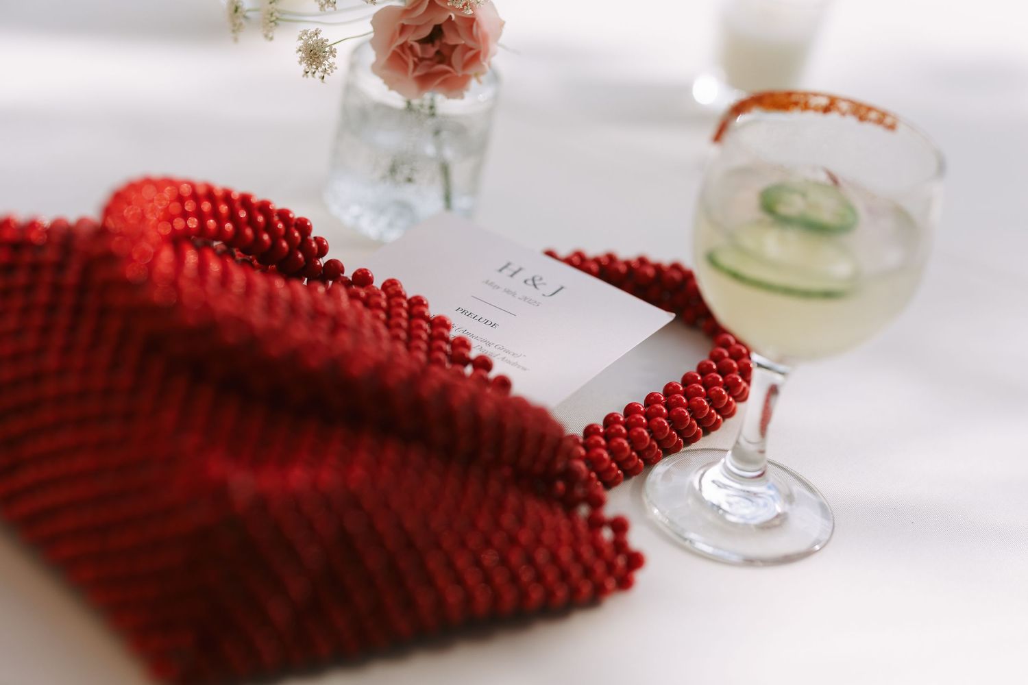 Close-up of wine glasses and a red knit napkin on a white tablecloth.